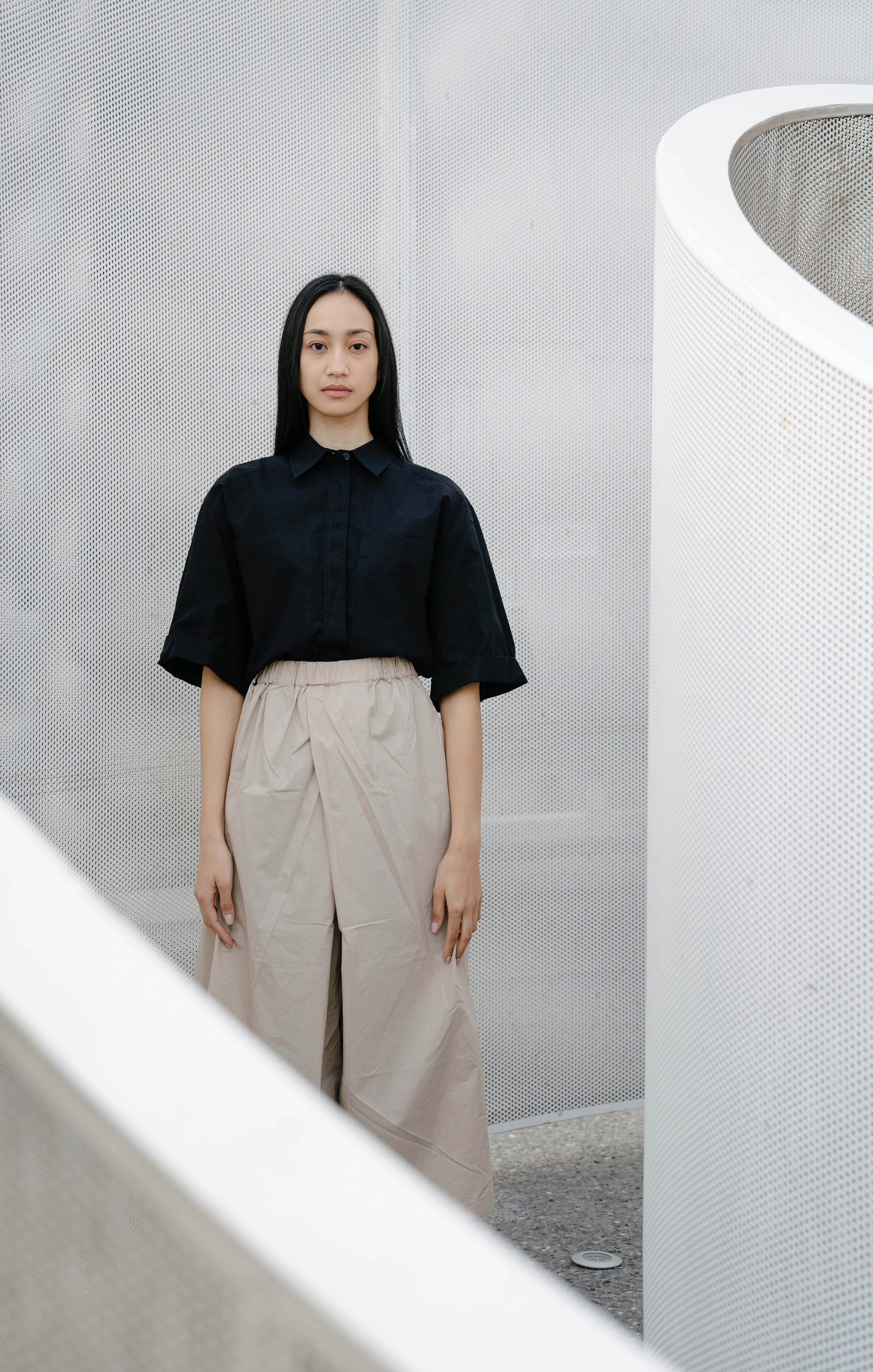 black blouse, beige pants, curved white architectural elements, 5K Phone Wallpaper