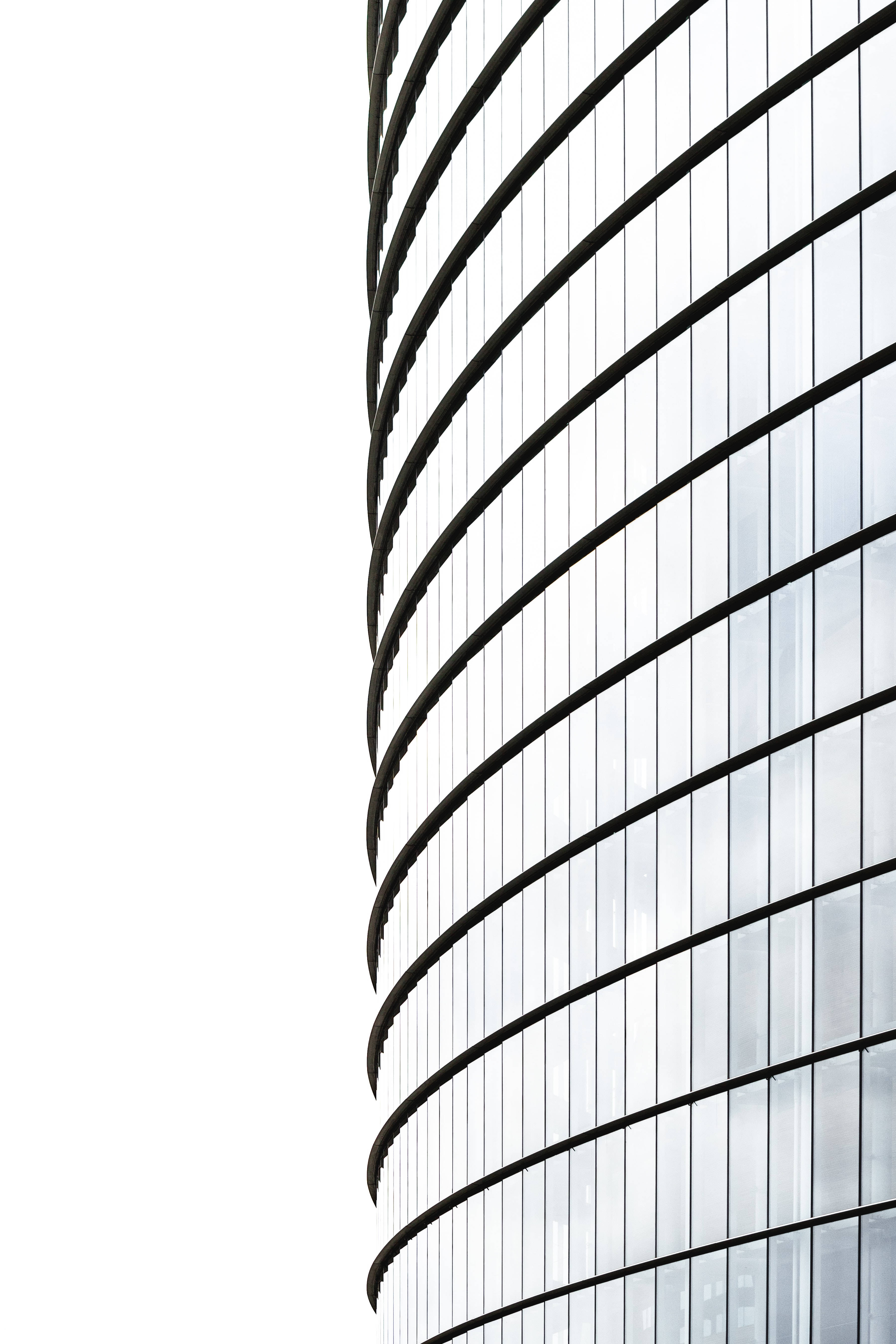 curved glass skyscraper, bold black framing, bright white sky, 5K Phone Wallpaper