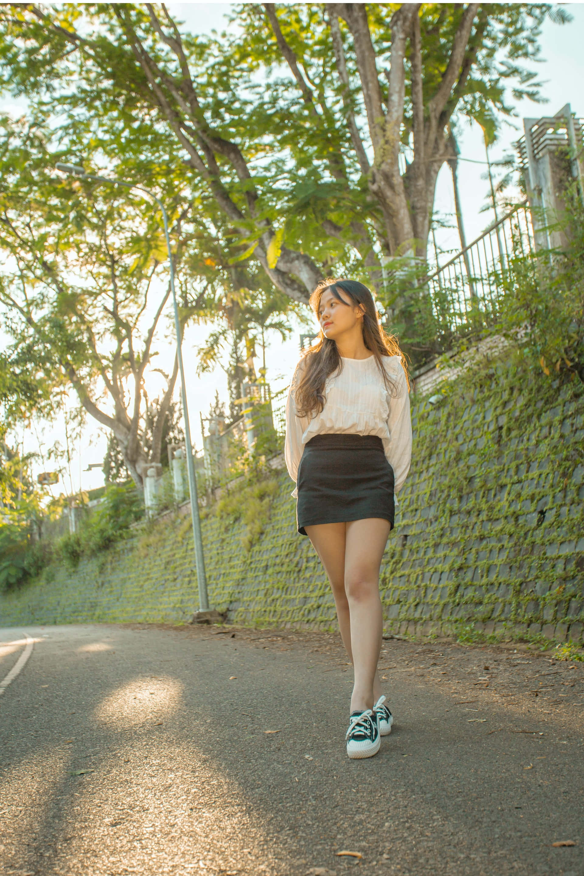 plain black miniskirt, young woman, tree-lined road, 2K Phone Wallpaper
