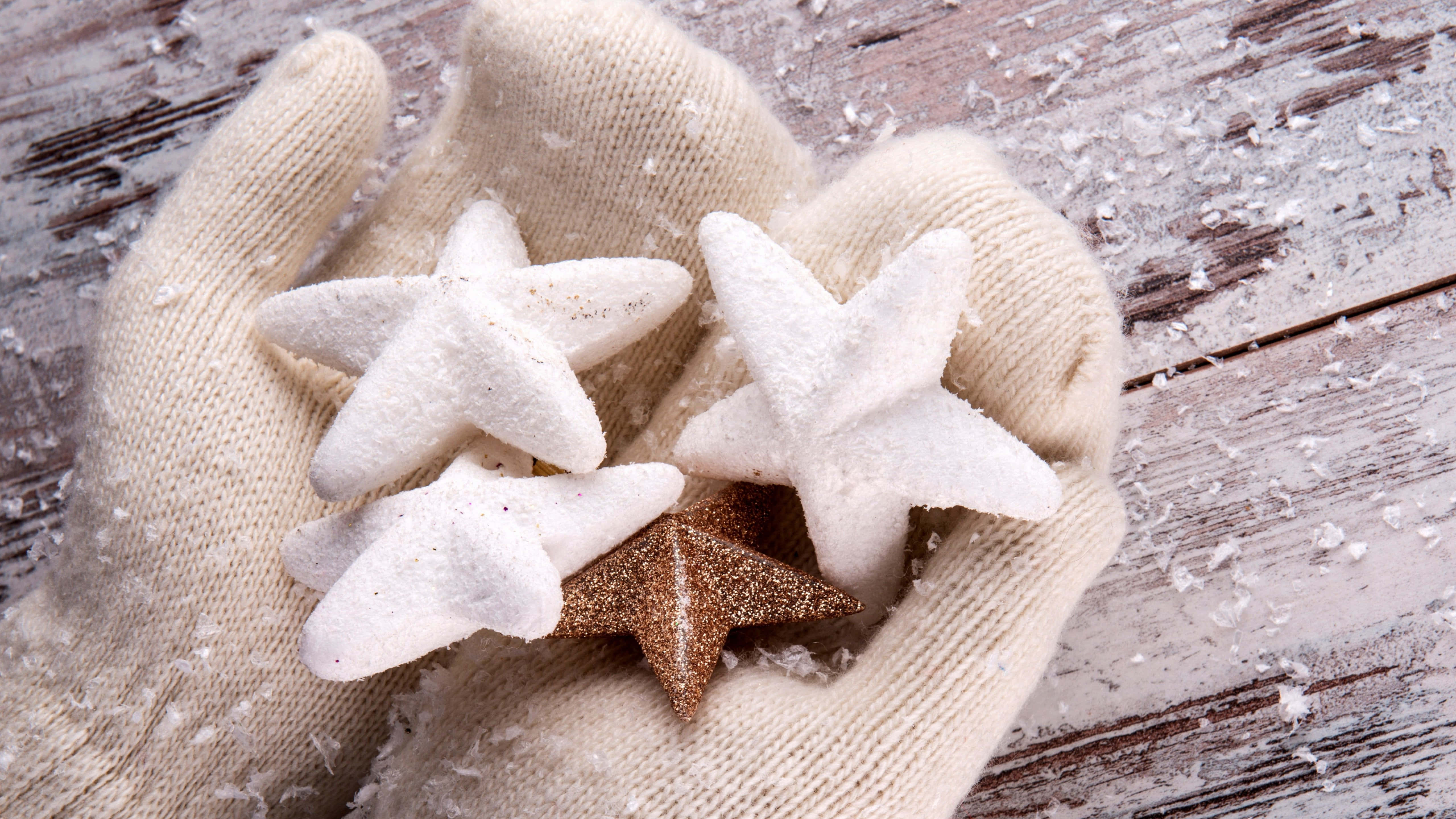 beige knit gloves, white and glittery star-shaped ornaments, snowy weathered wooden surface, 5K Desktop Wallpaper