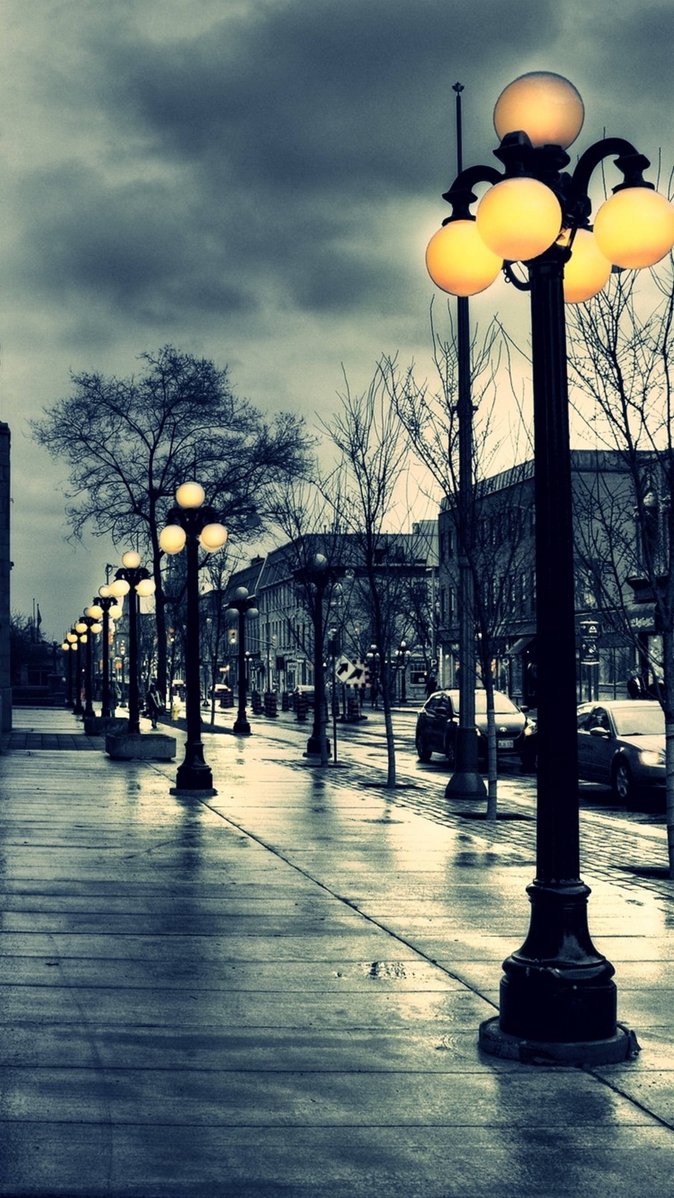 Mobile 4K, wet urban sidewalk, glowing vintage street lamps, 4K Phone Wallpaper