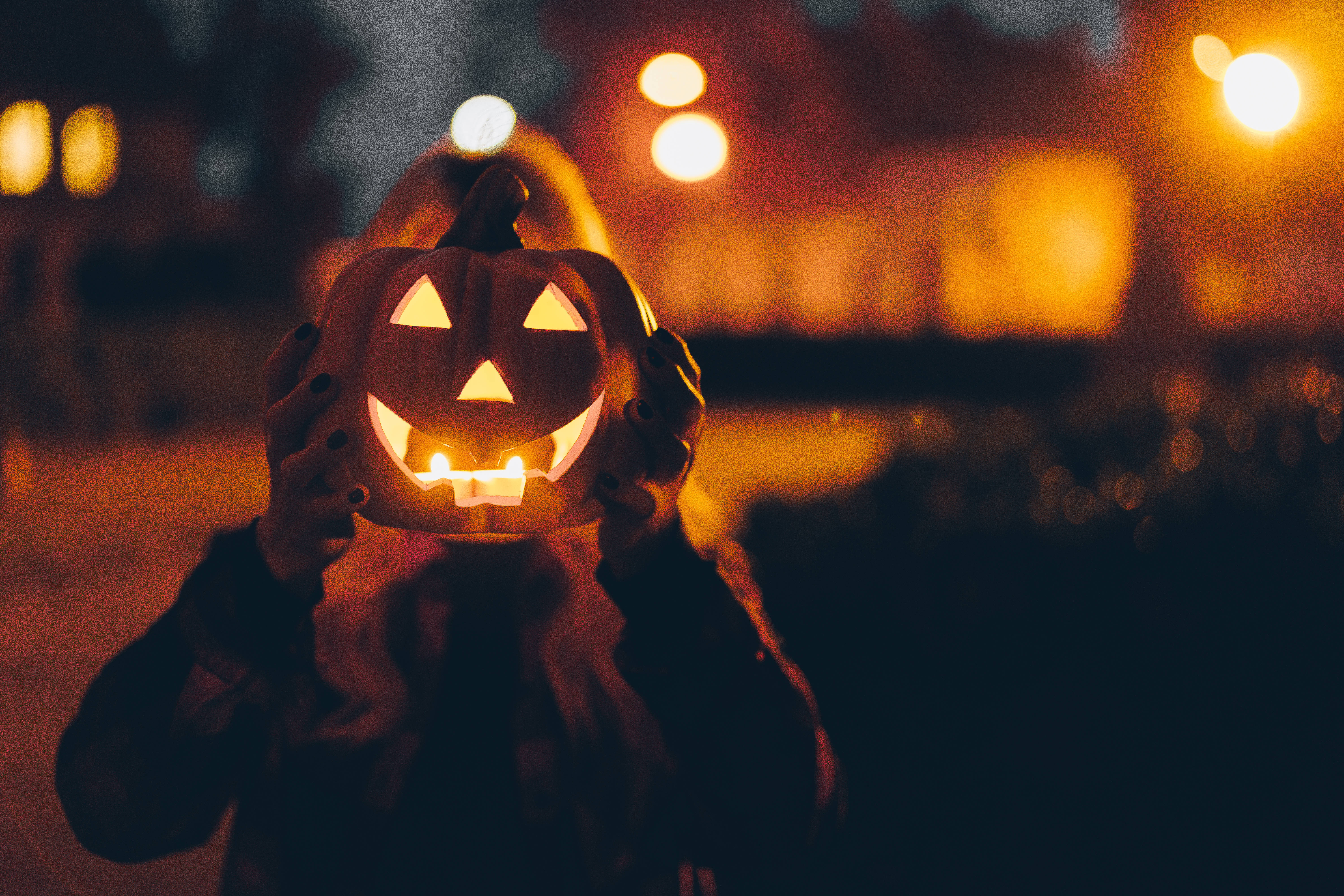 glowing jack-o'-lantern, candle, warm bokeh-lit night street, 5K Desktop Wallpaper