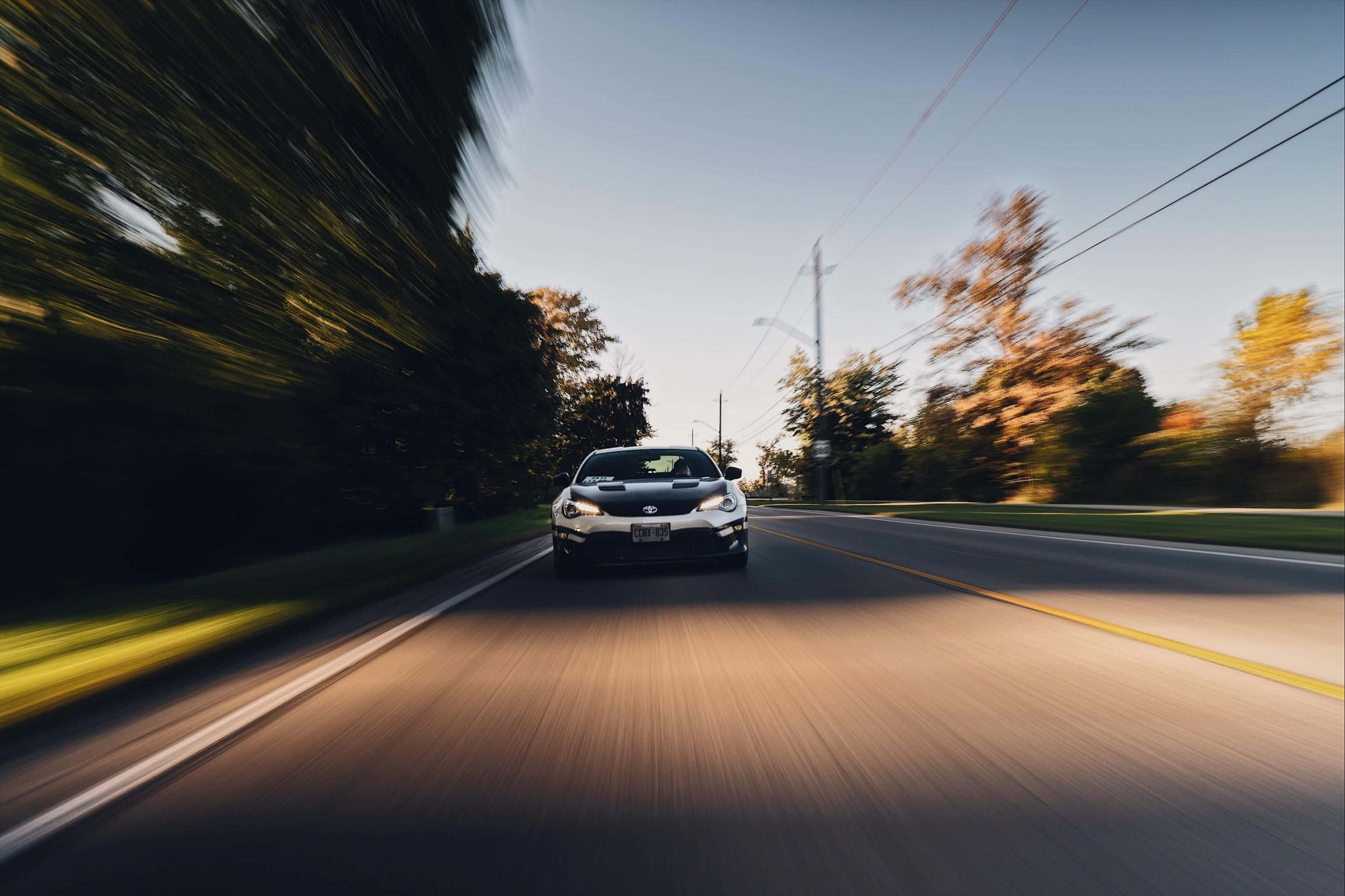 silver sports car, sunlit road, blurred autumn trees, 2K Desktop Wallpaper