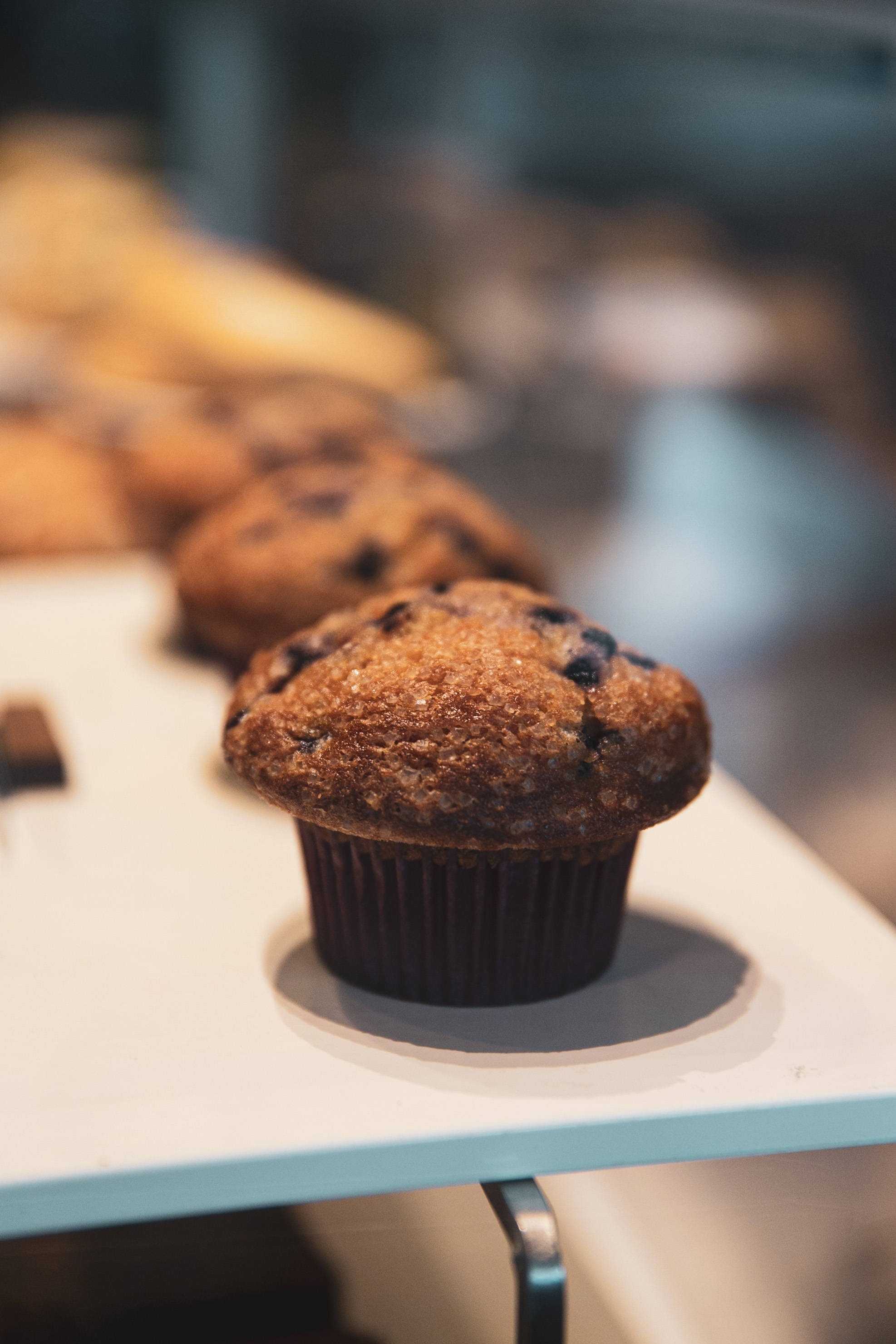 golden brown blueberry muffin, sugar crystals, white bakery display shelf, 2K Phone Wallpaper