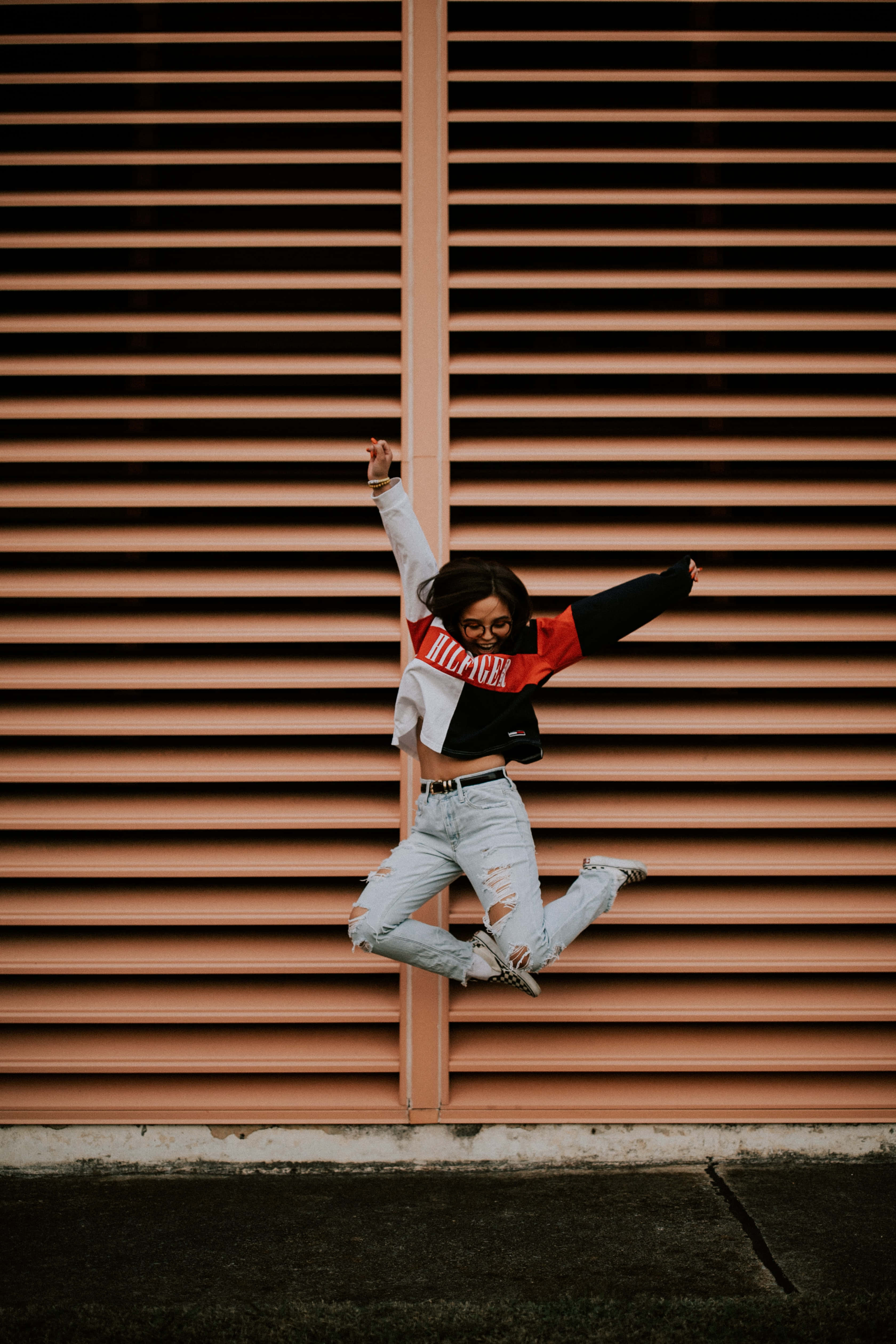 Mujer Soltera, salmon-colored metal shutter wall, dynamic urban pose, 4K Phone Wallpaper