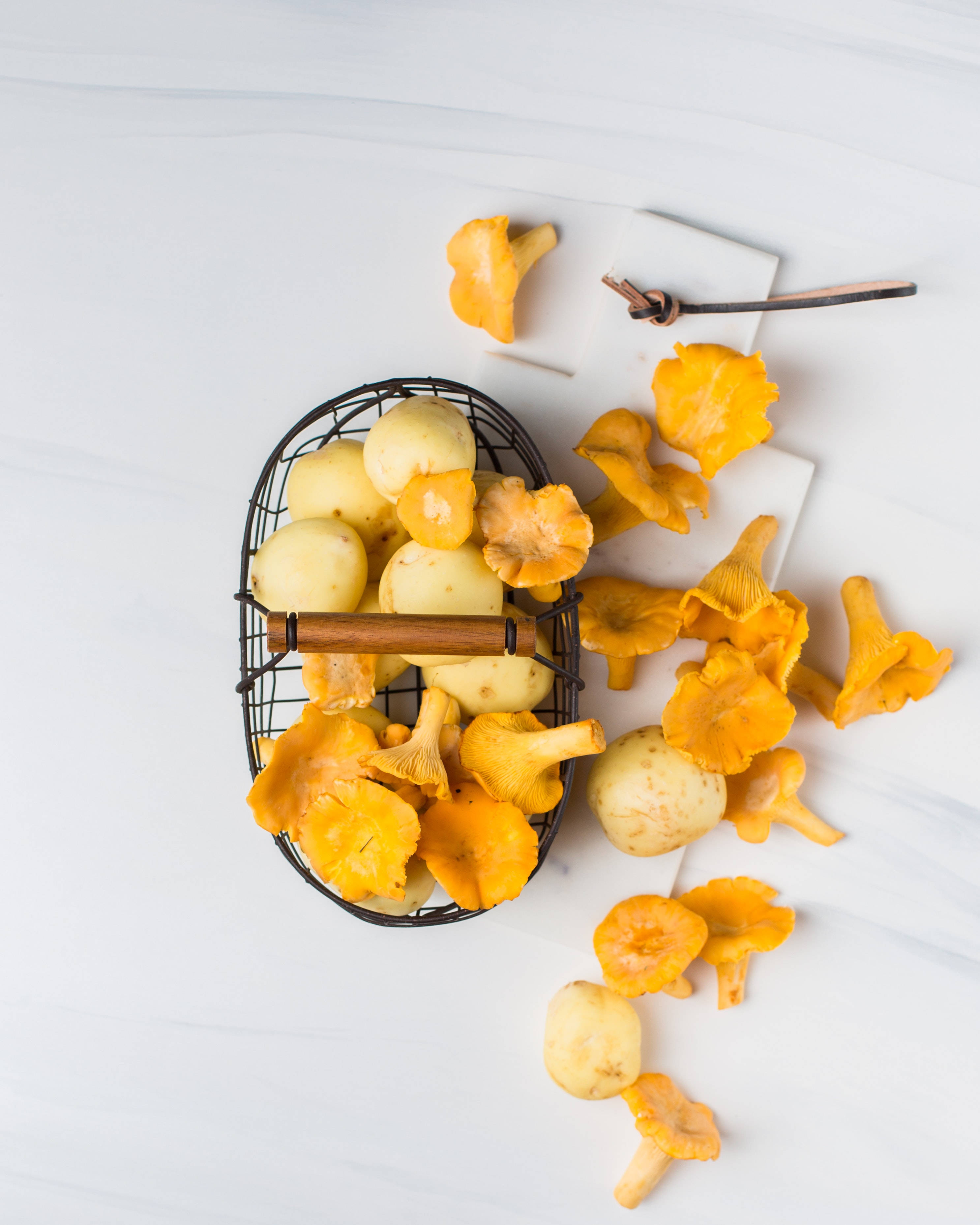 yellow chanterelle mushroom, wire basket, white marble surface, 2K Phone Wallpaper