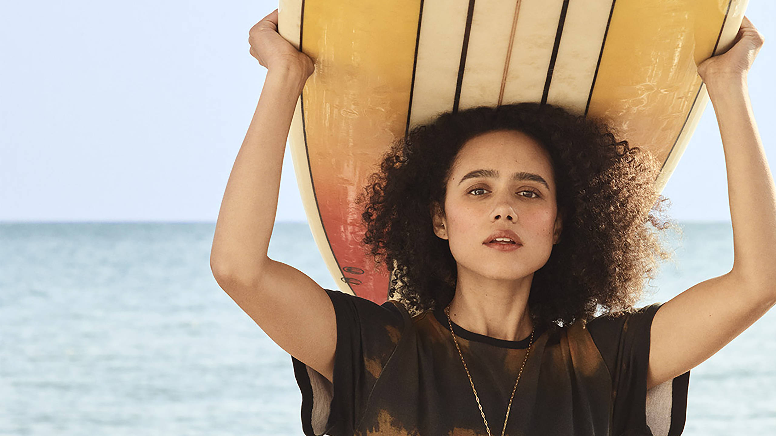 Nathalie Emmanuel, yellow surfboard, calm ocean backdrop, 2K Desktop Wallpaper