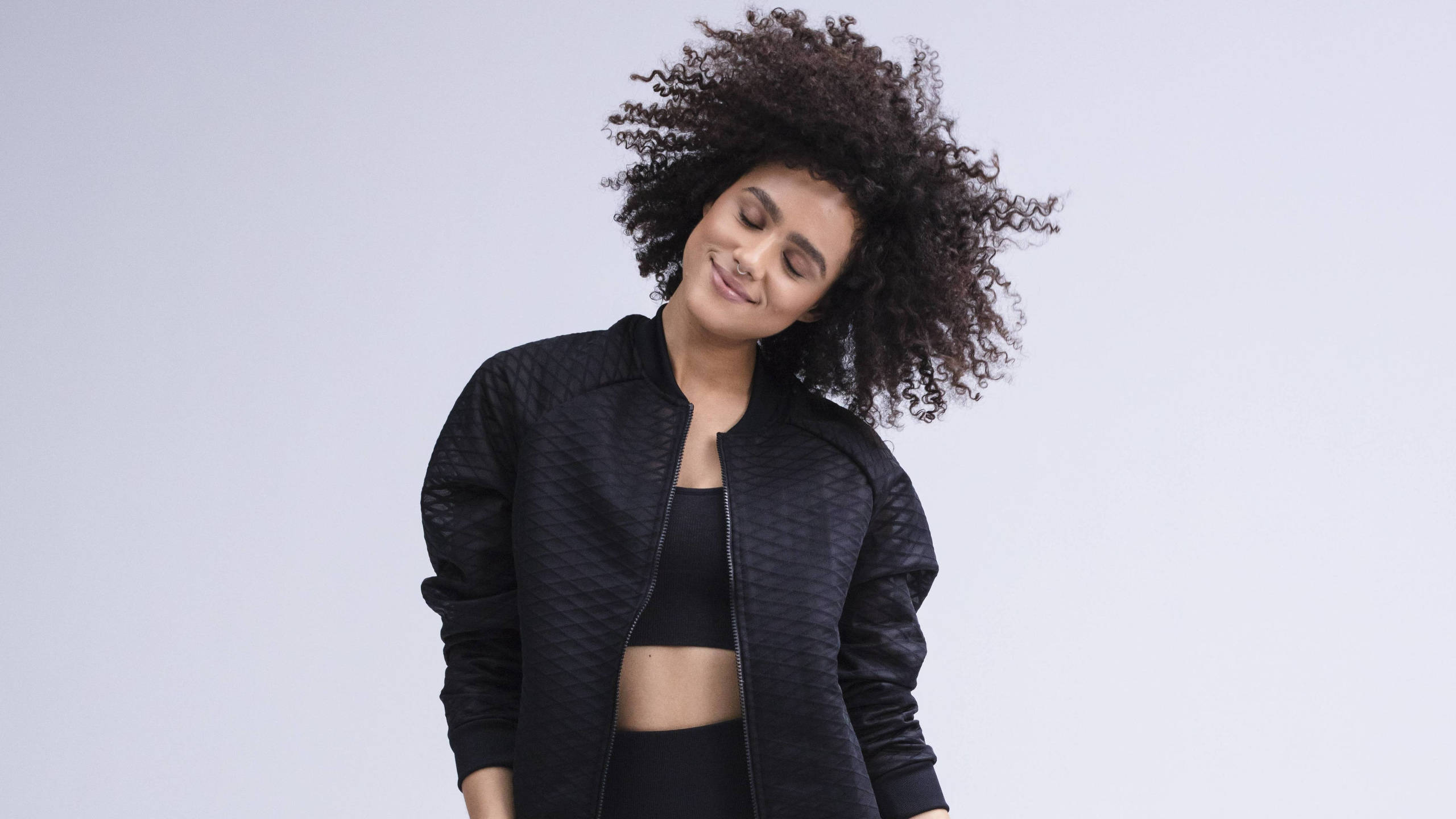 Nathalie Emmanuel, voluminous curly hair, black textured bomber jacket, 2K Desktop Wallpaper