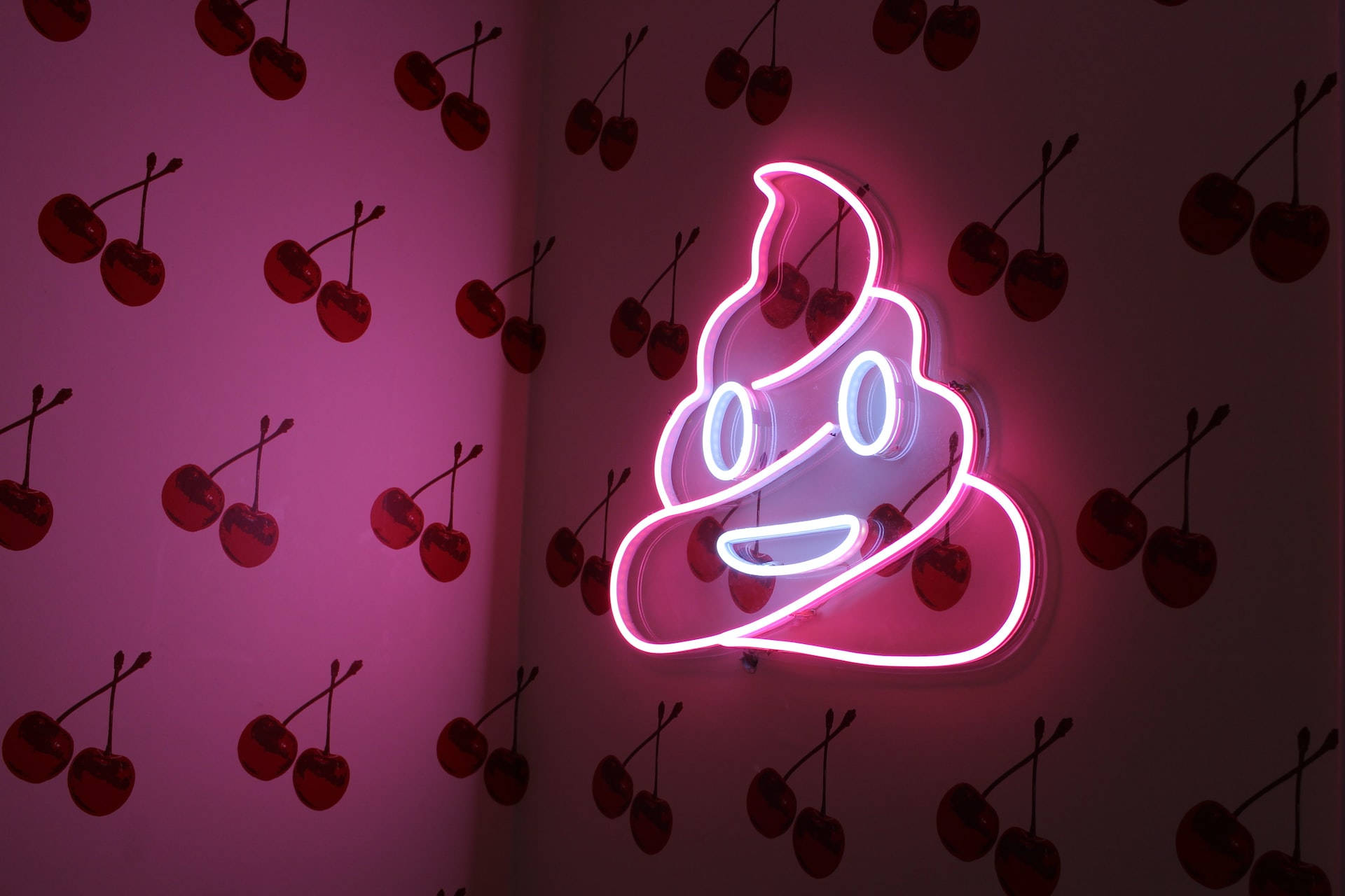 Poo Neon Smile, glowing pink and white poop emoji neon sign, wall covered in cherry decals, Full HD Desktop Wallpaper