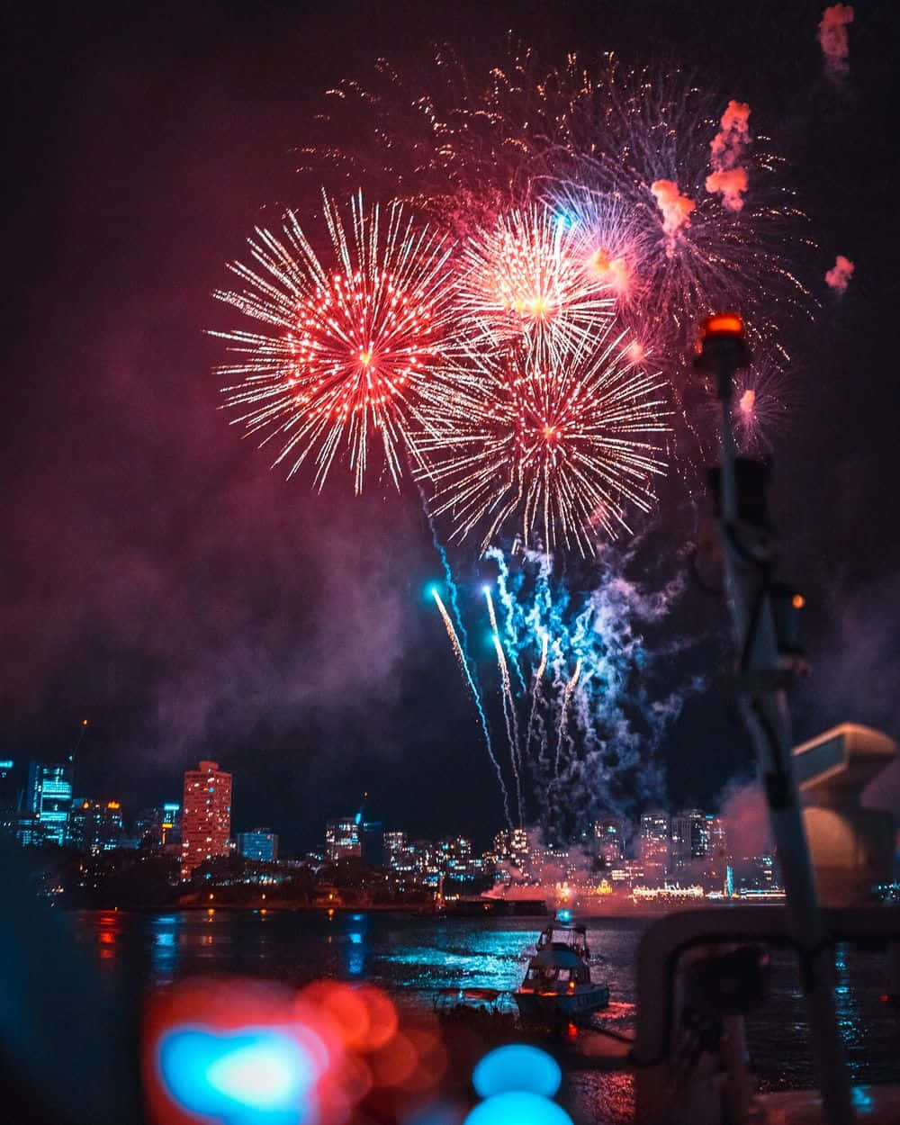 golden iPhone, Vibrant red and blue fireworks, city skyline, SD Phone Wallpaper