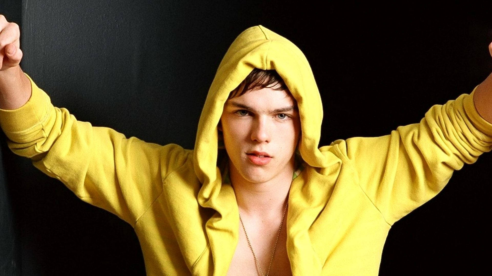 Nicholas Hoult, bright yellow hoodie, arms raised, Full HD Desktop Wallpaper