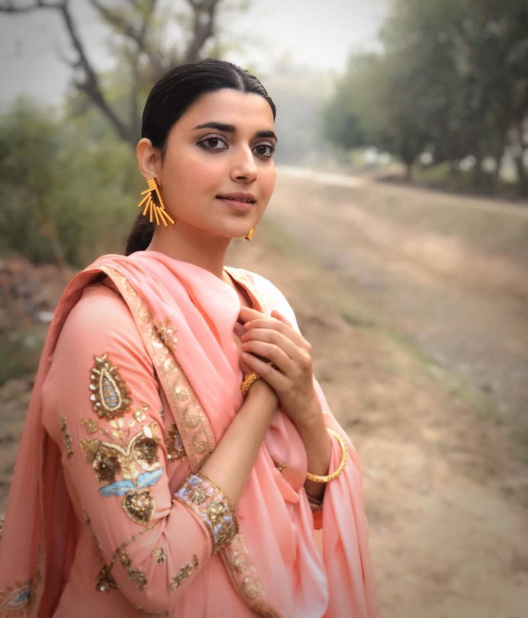 Nimrat Khaira, pink embroidered traditional outfit, tree-lined dirt path, SD Phone Wallpaper