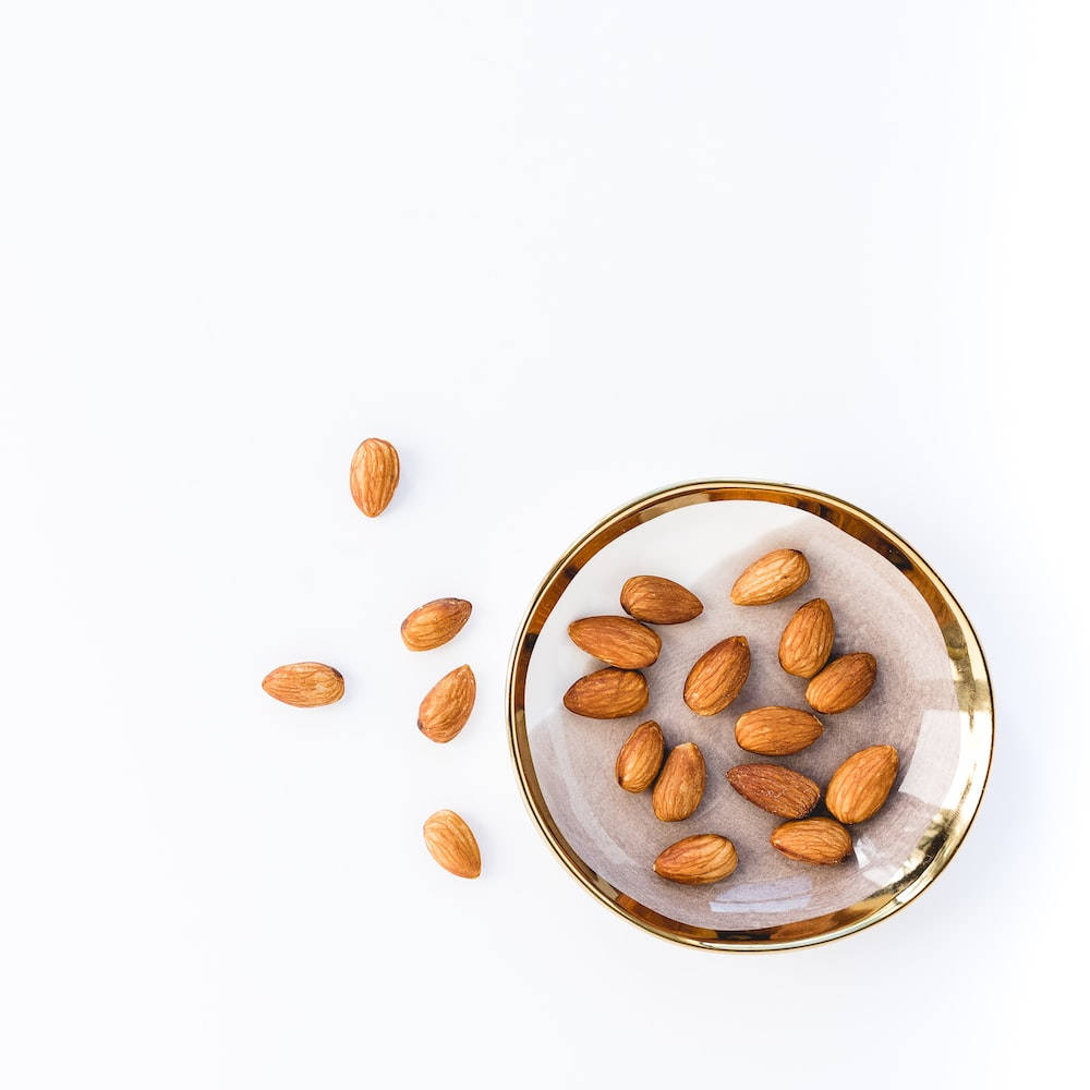 almond nuts, gold-rimmed glass dish, pristine white surface, SD Desktop Wallpaper