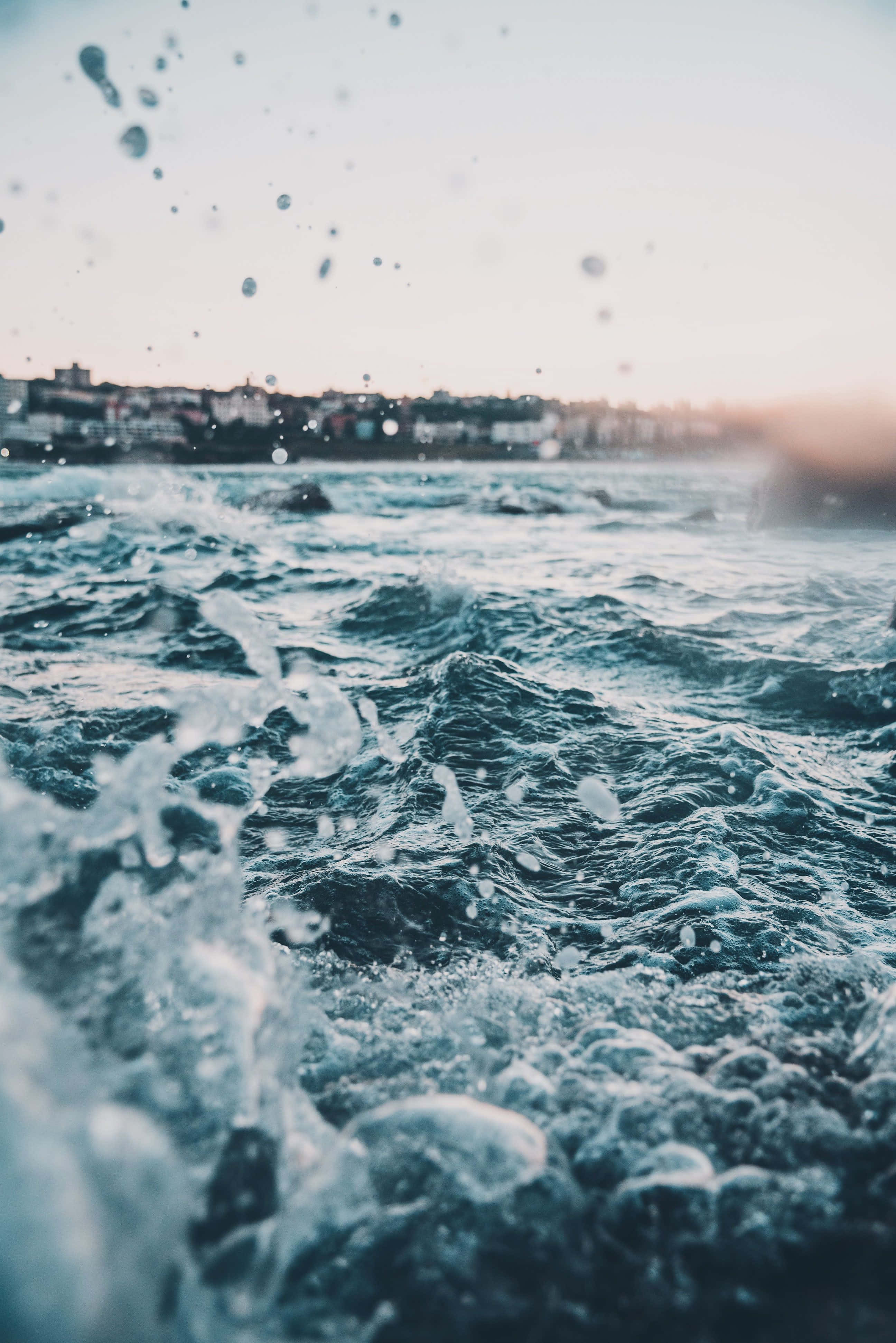 ocean waves, droplets suspended in air, hazy coastal town, 4K Phone Wallpaper