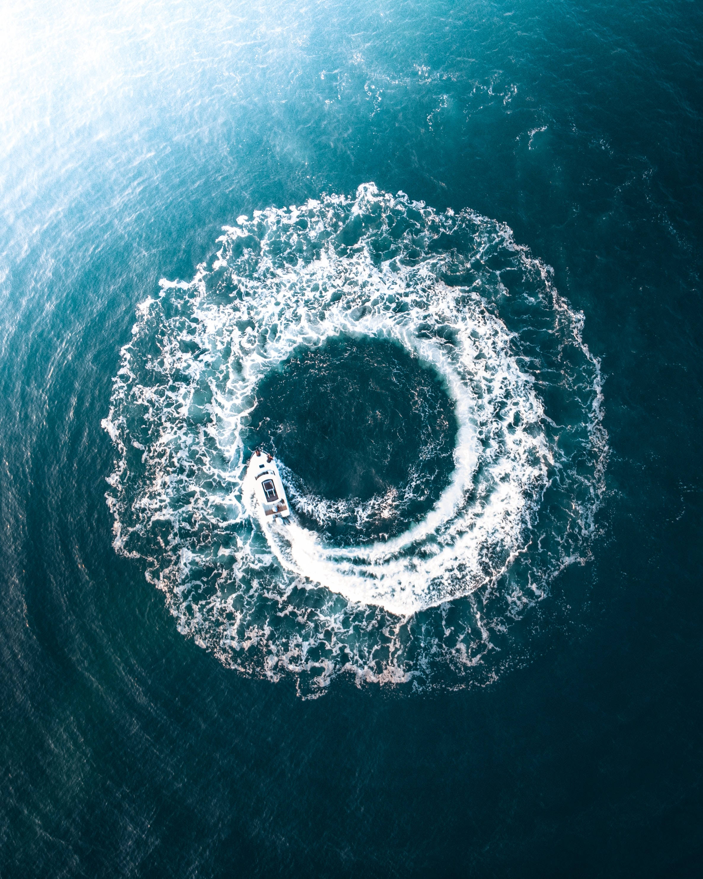 white speedboat, deep blue ocean water, aerial view, 2K Phone Wallpaper