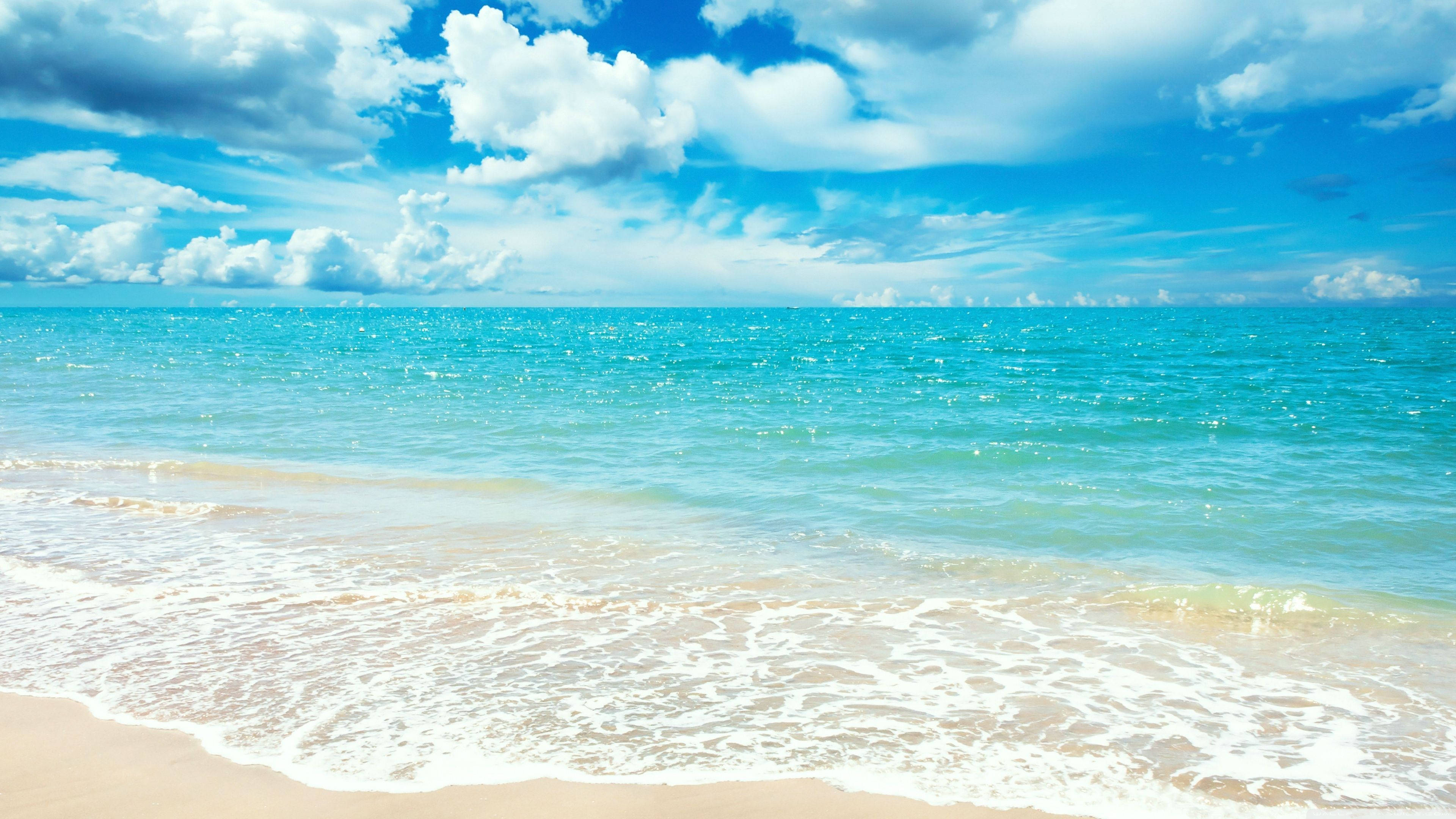 Sunlit turquoise waves, golden sandy beach, vibrant blue sky, 4K Desktop Wallpaper