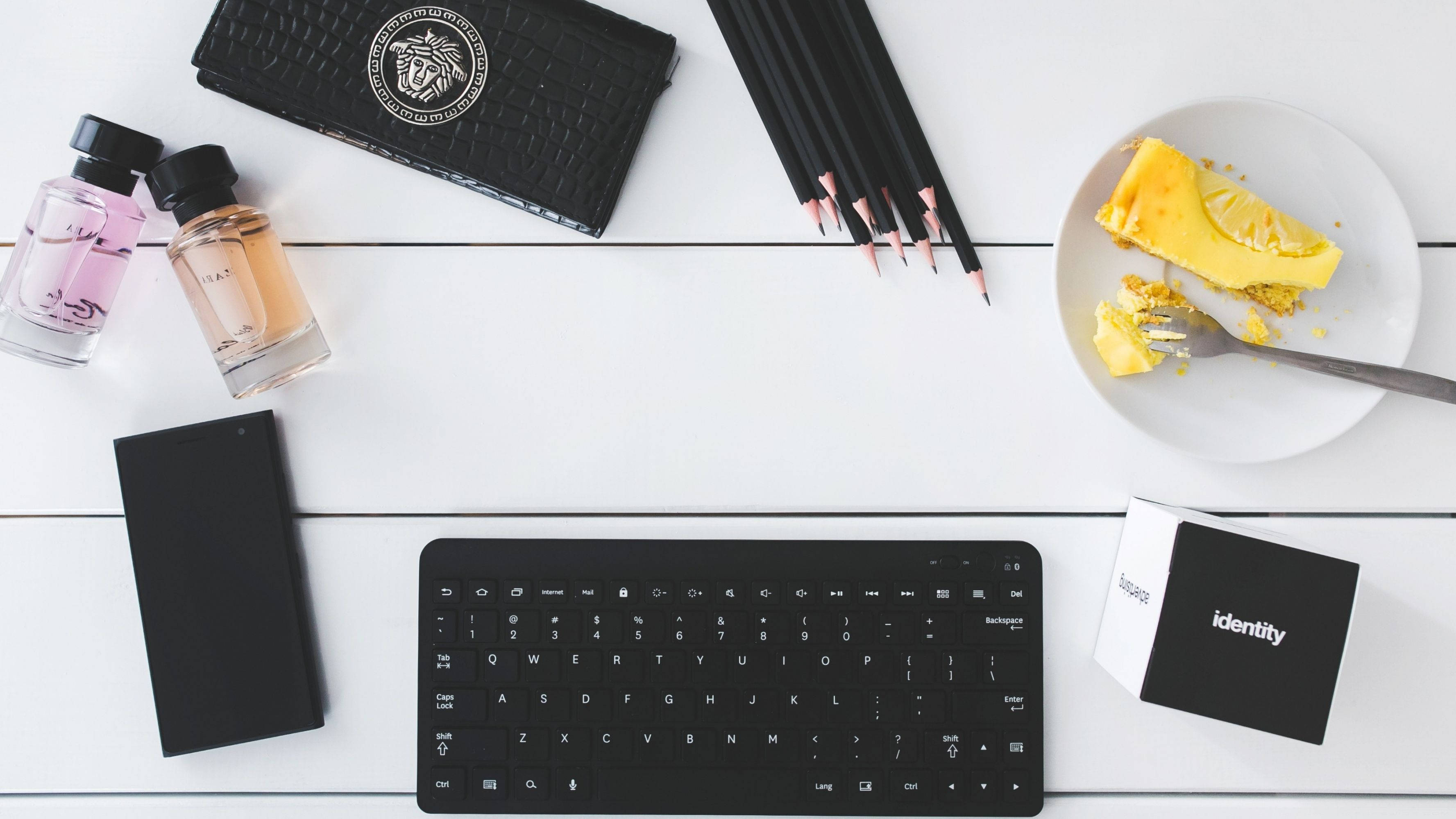 white wooden office desk, black keyboard, perfume bottles, 2K Desktop Wallpaper