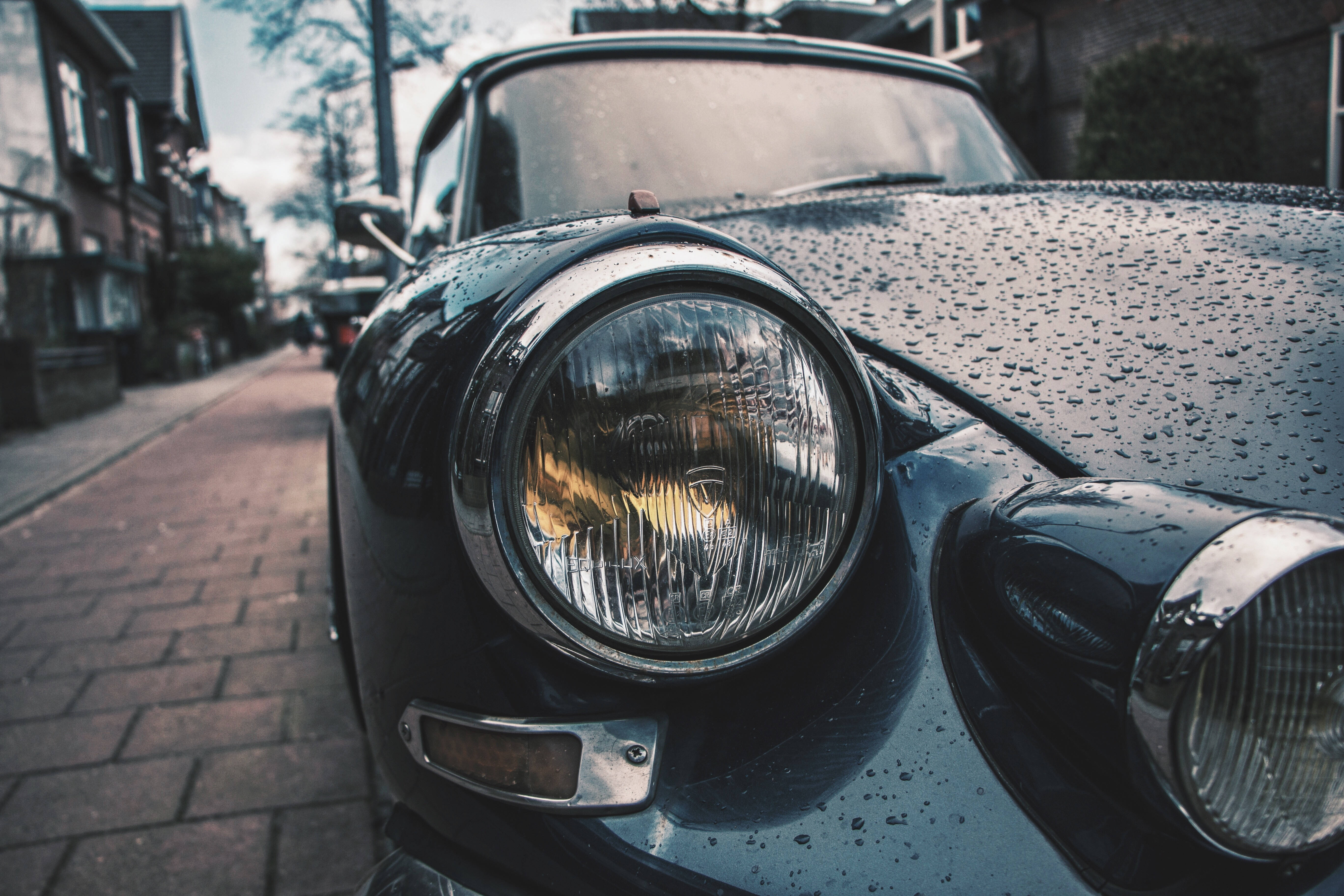 vintage black car, wet chrome headlight, rainy street scene, 5K Desktop Wallpaper