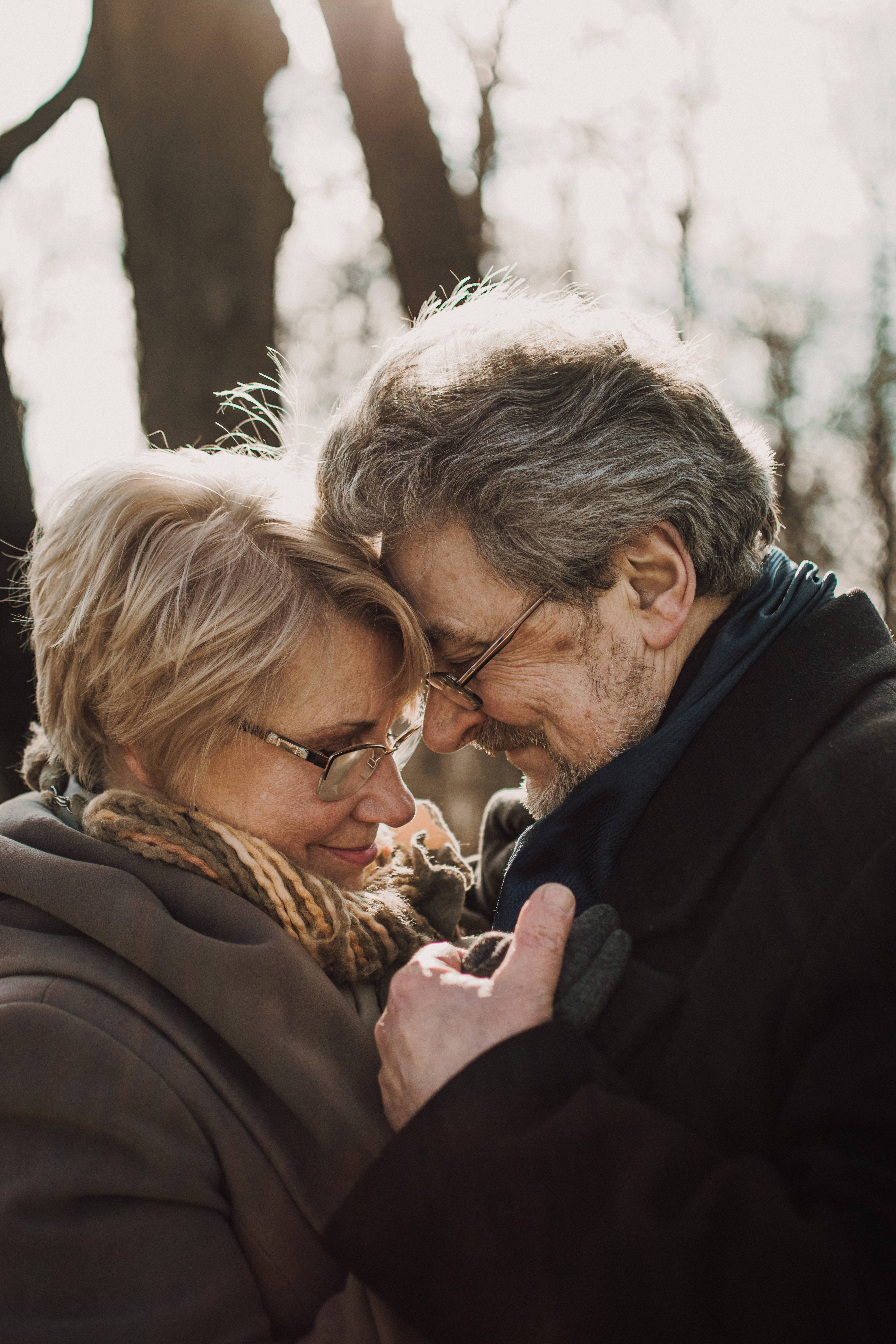 Old Couple, foreheads touching, sunlit winter forest, 5K Phone Wallpaper