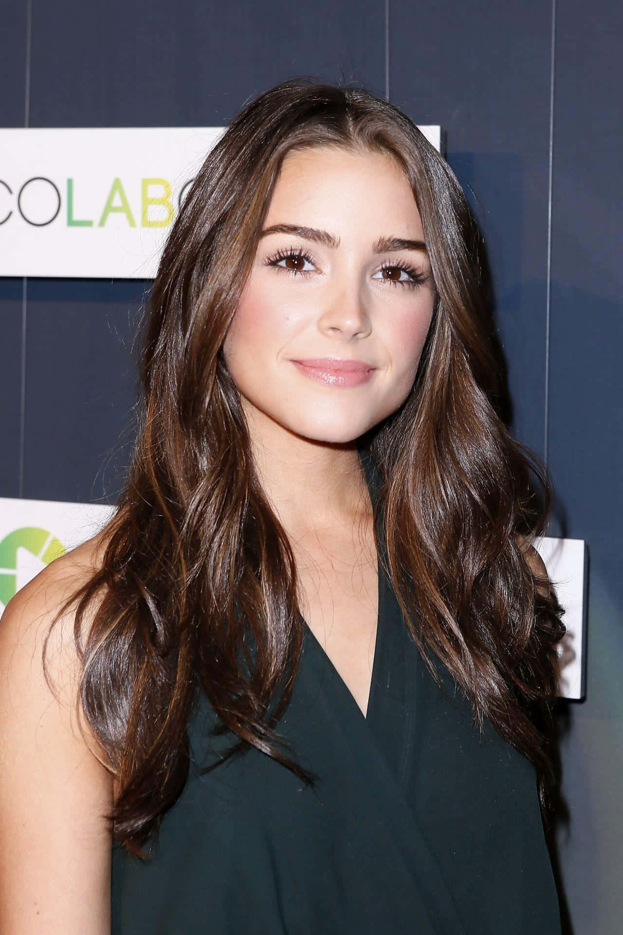 Olivia Culpo, dark green sleeveless top, long wavy brown hair, Full HD Phone Wallpaper