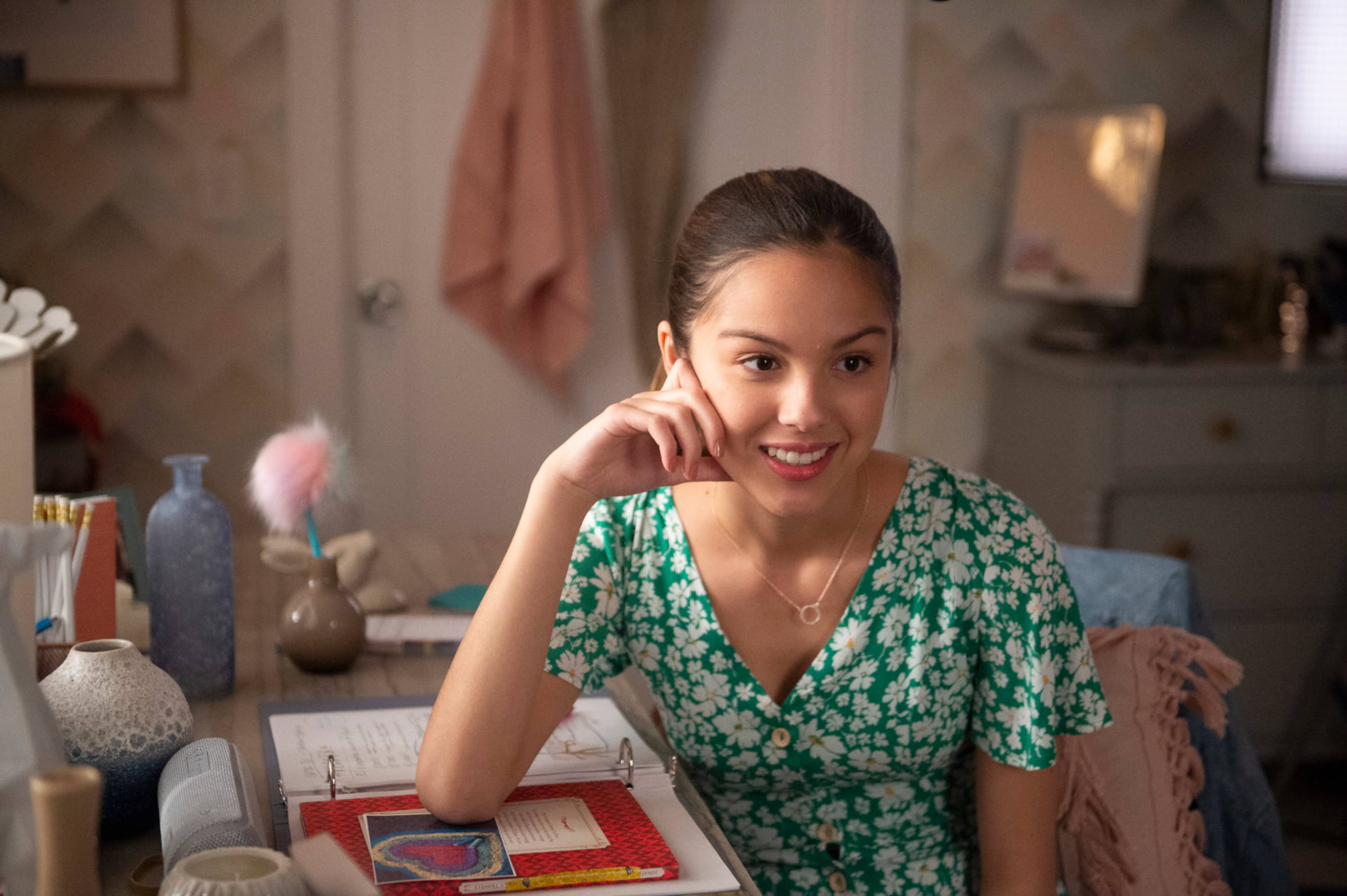 Olivia Rodrigo, green floral dress, cluttered desk, 5K Desktop Wallpaper