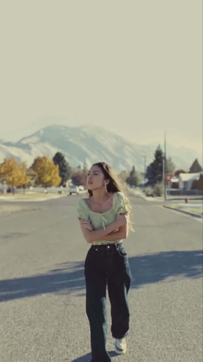 Olivia Rodrigo, sunlit street, mountains, SD Phone Wallpaper