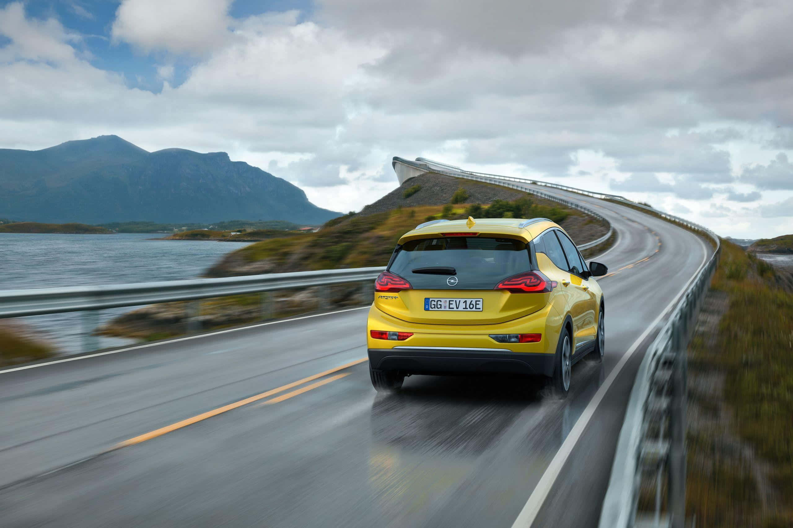 Opel Ampera, vibrant yellow, winding coastal road, 2K Desktop Wallpaper