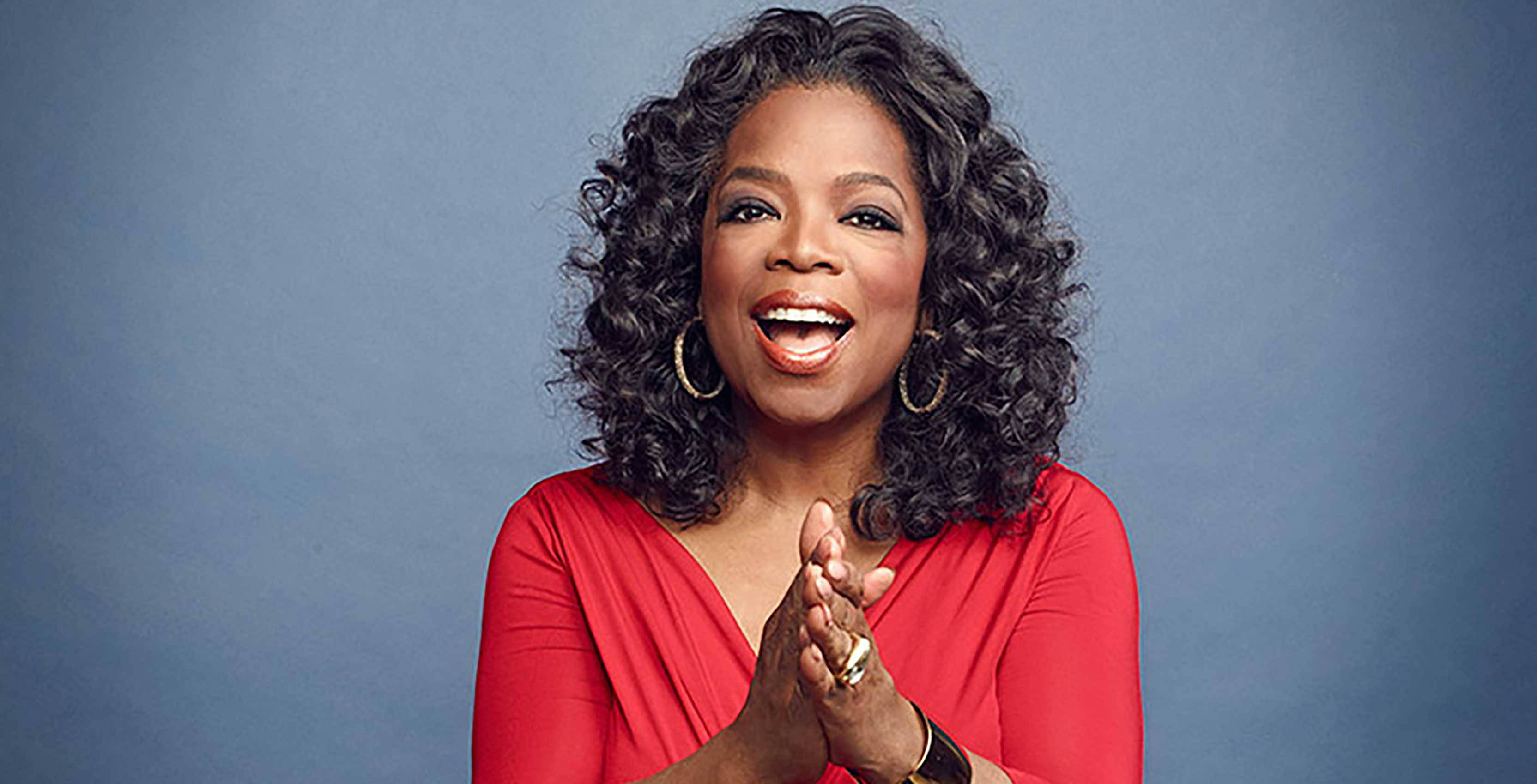 Oprah Winfrey, vibrant red top, soft blue studio backdrop, 2K Desktop Wallpaper