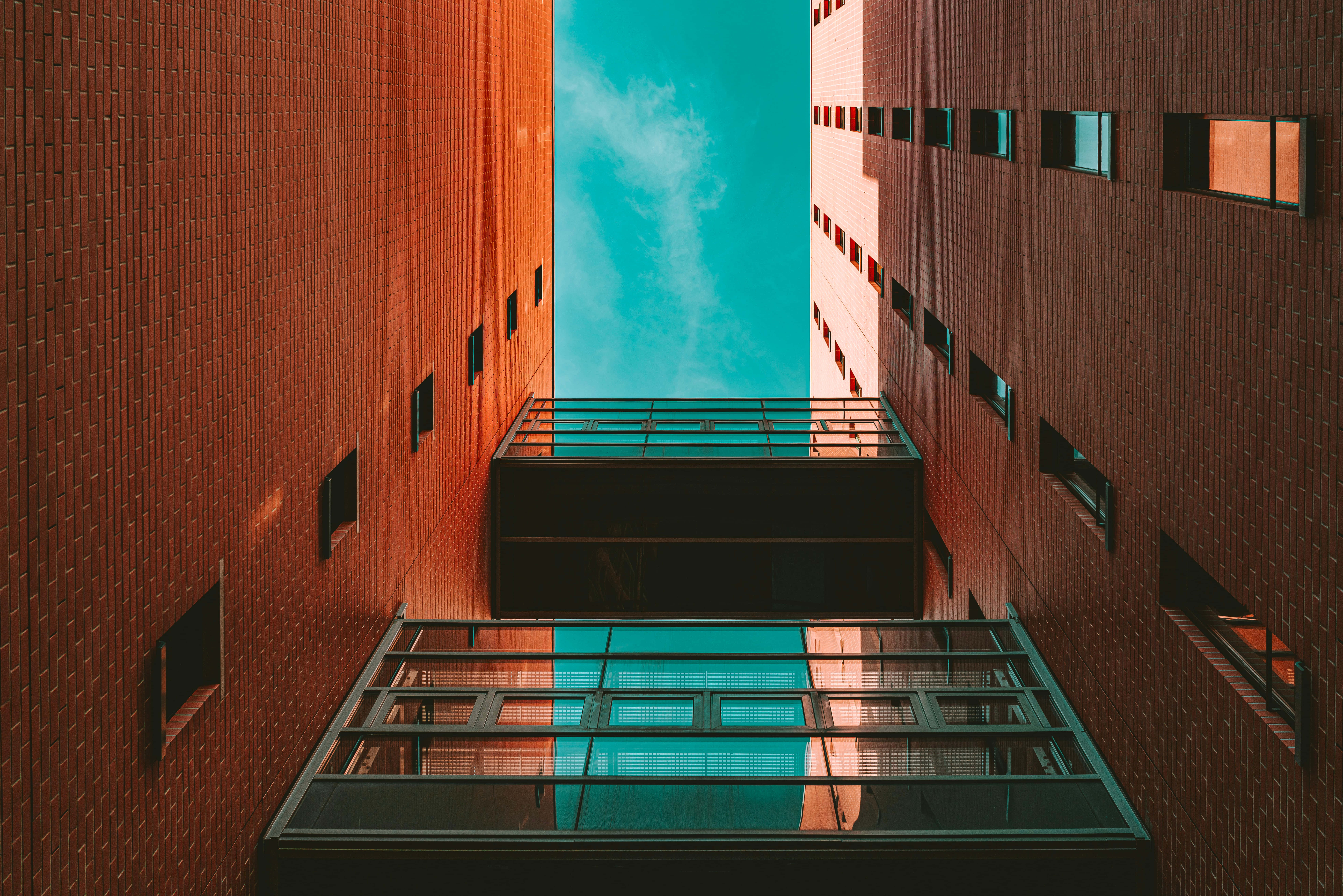 red brick buildings, vibrant turquoise sky, glass balconies, 8K Desktop Wallpaper