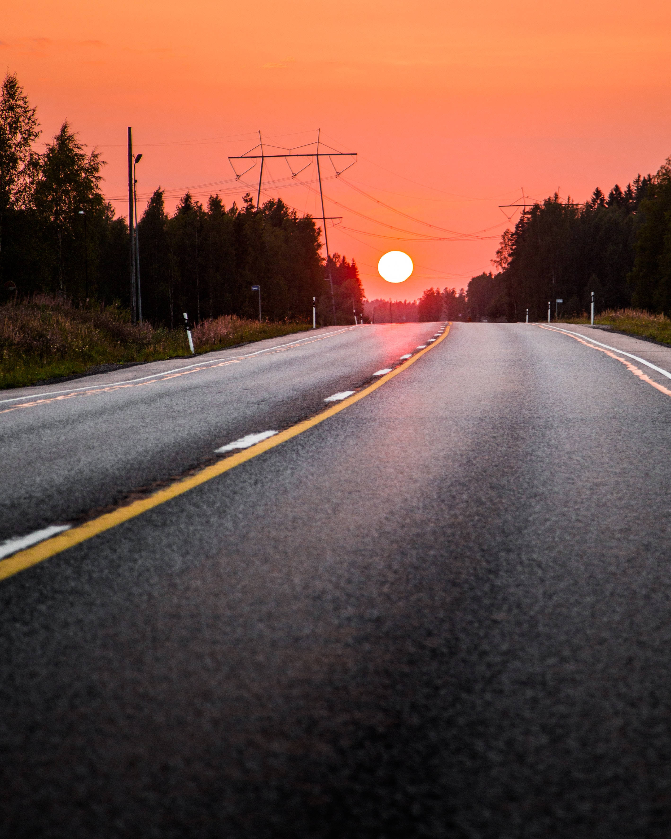 Orange Sun, winding asphalt road, forested horizon, 2K Phone Wallpaper