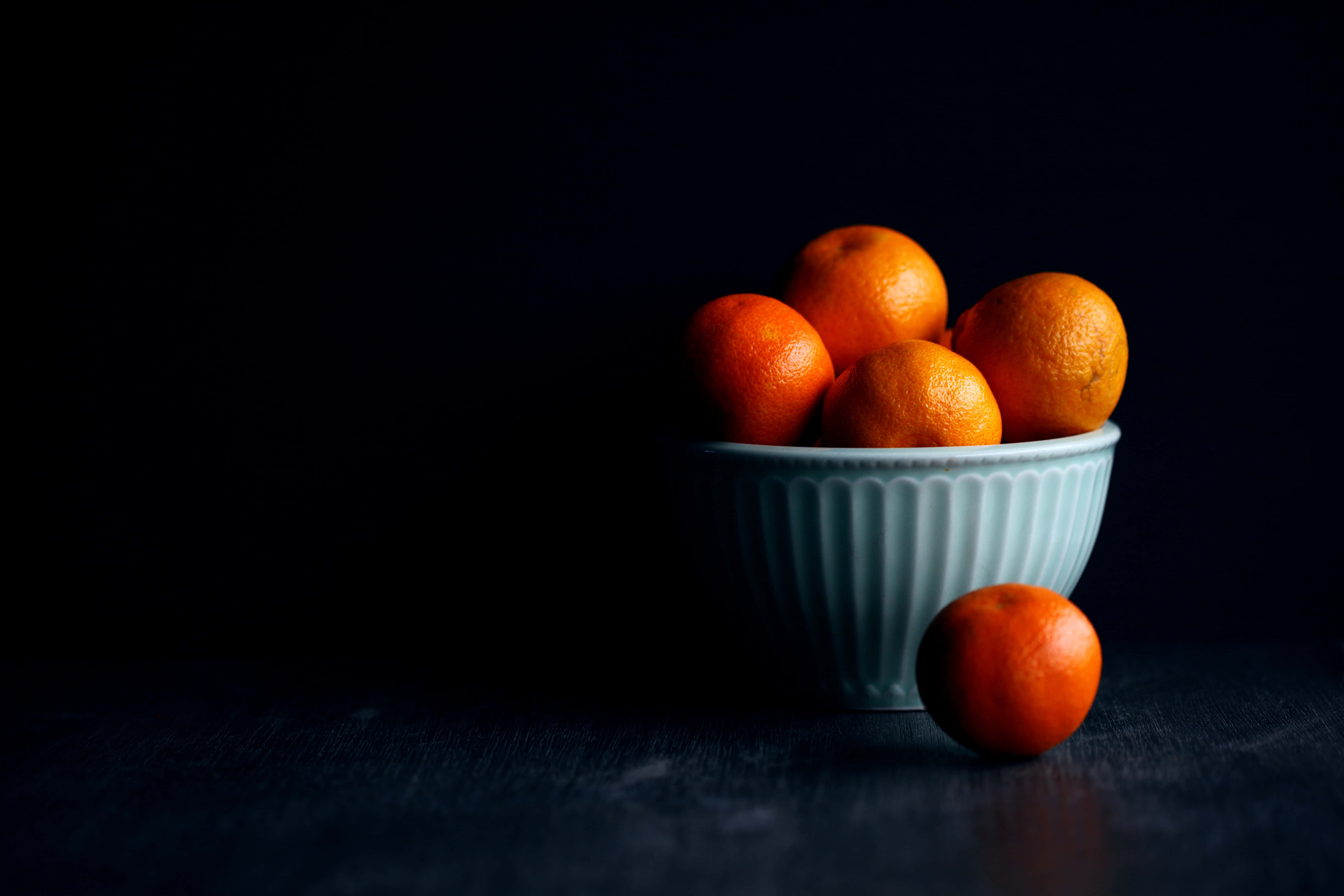 light blue ribbed bowl, vibrant orange tangerines, deep black background, 5K Desktop Wallpaper