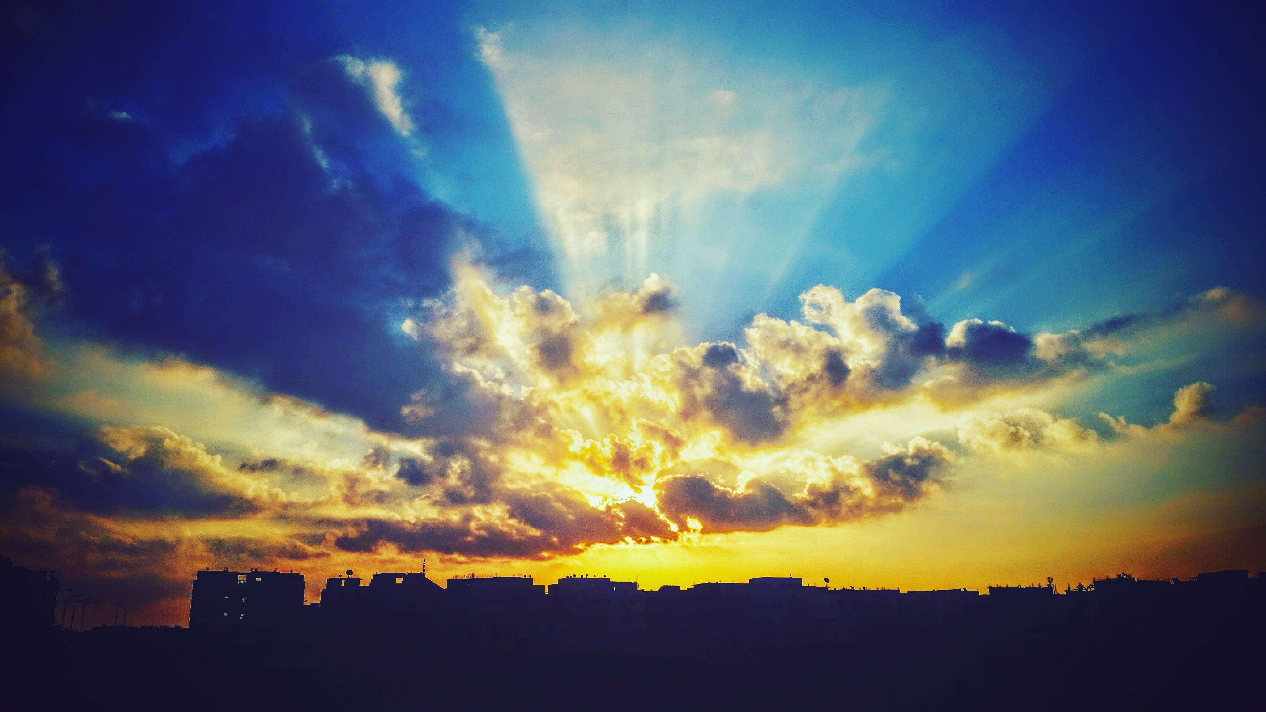 sunburst rays, dramatic clouds, city skyline, 4K Desktop Wallpaper