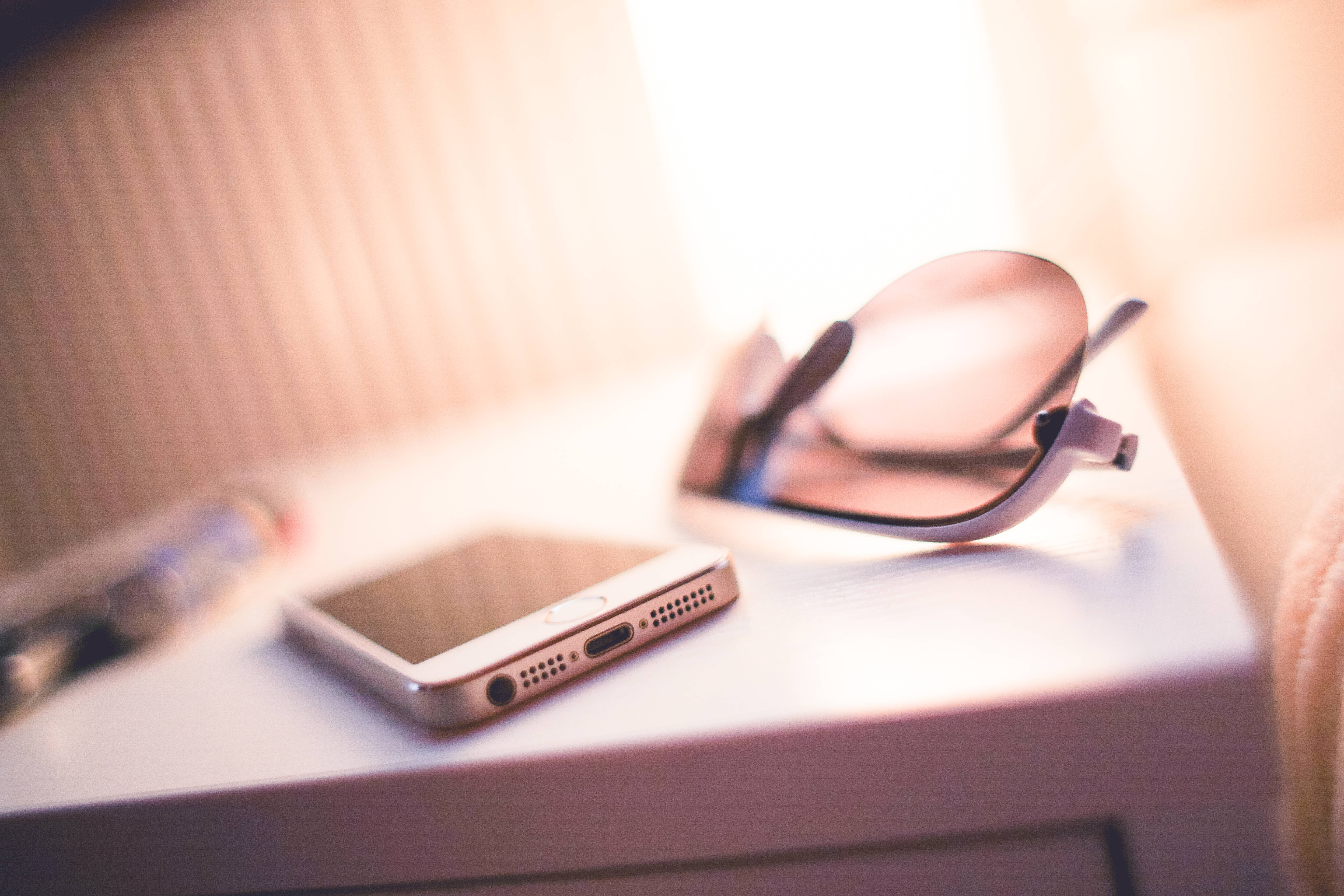 Original iPhone 5, white surface, warm golden light, 5K Desktop Wallpaper