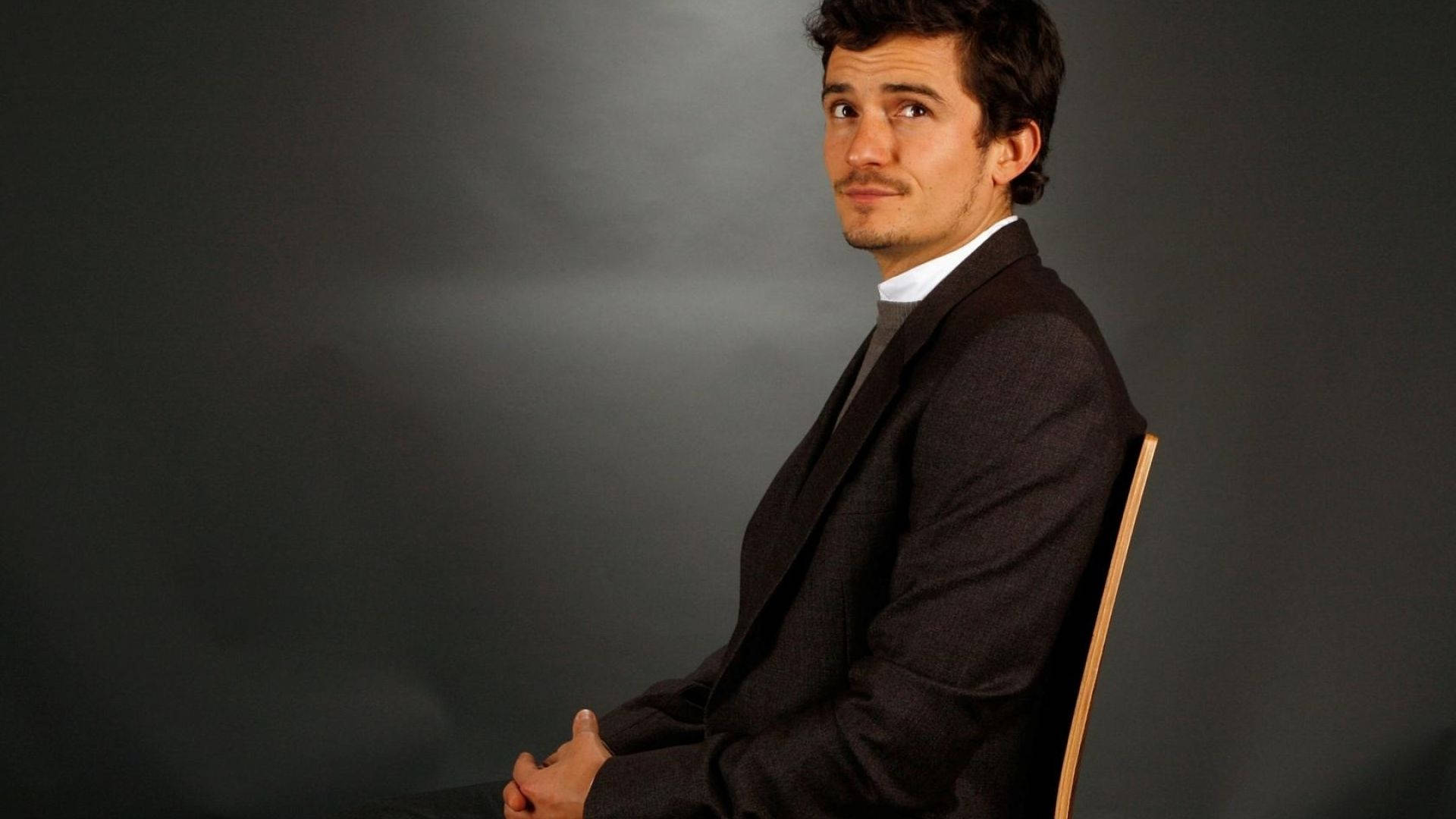 Orlando Bloom, dark suit, wooden chair, Full HD Desktop Wallpaper