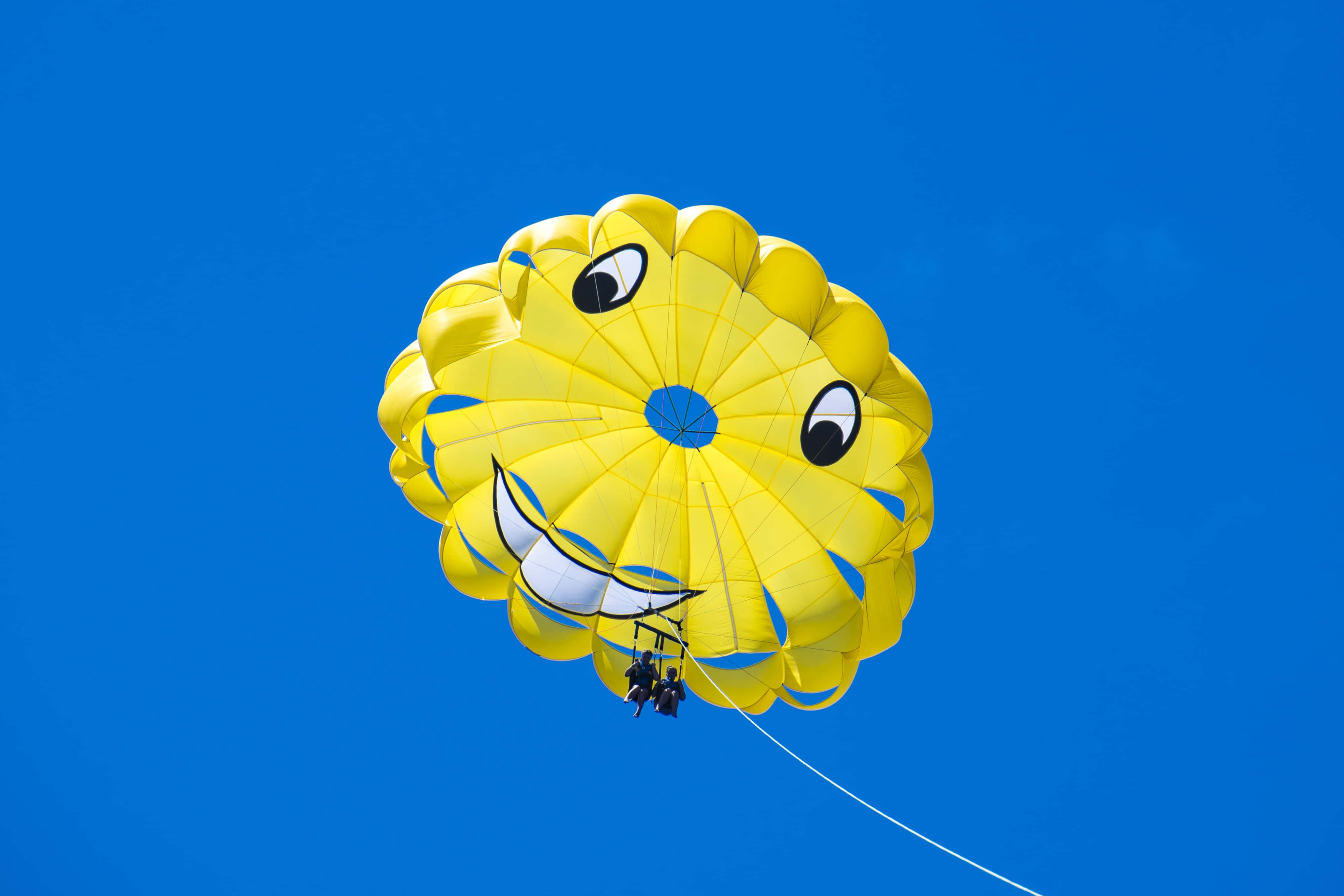bright yellow parasail, smiling face, vivid blue sky, 4K Desktop Wallpaper