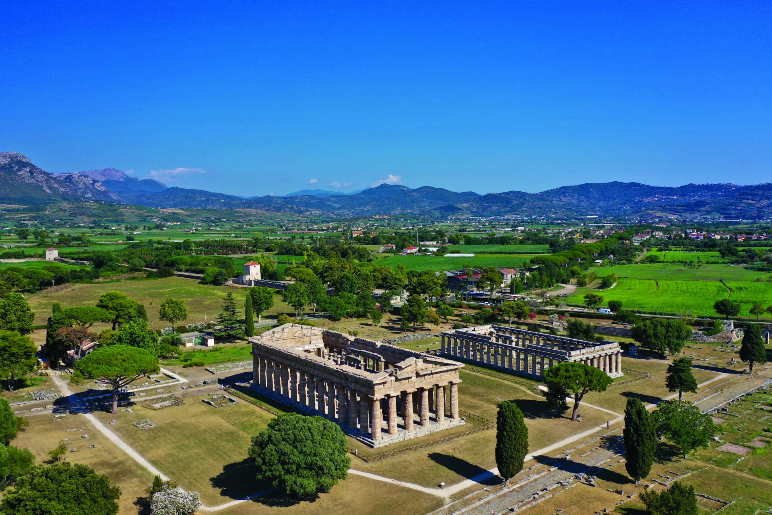 Paestum, ancient Greek temple ruins, lush green fields, 2K Desktop Wallpaper