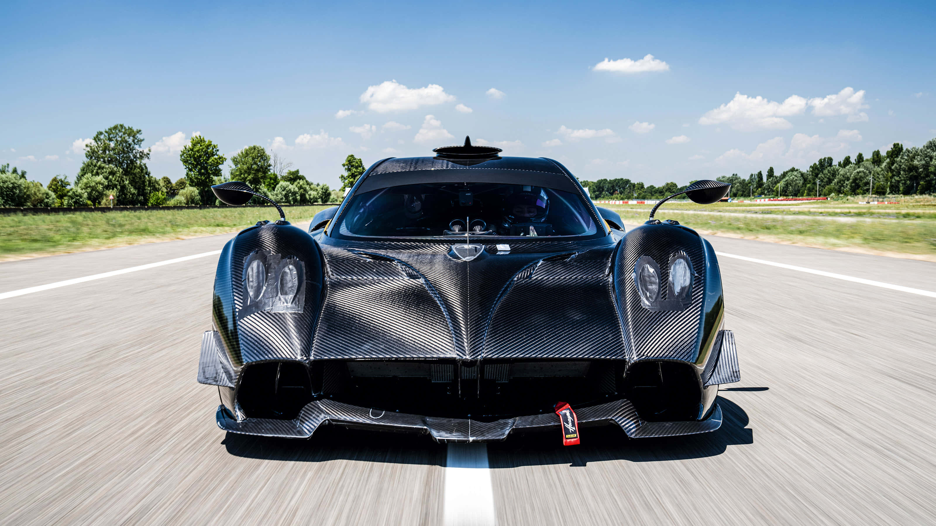 Pagani Huayra, black carbon fiber, sunlit racetrack, 2K Desktop Wallpaper