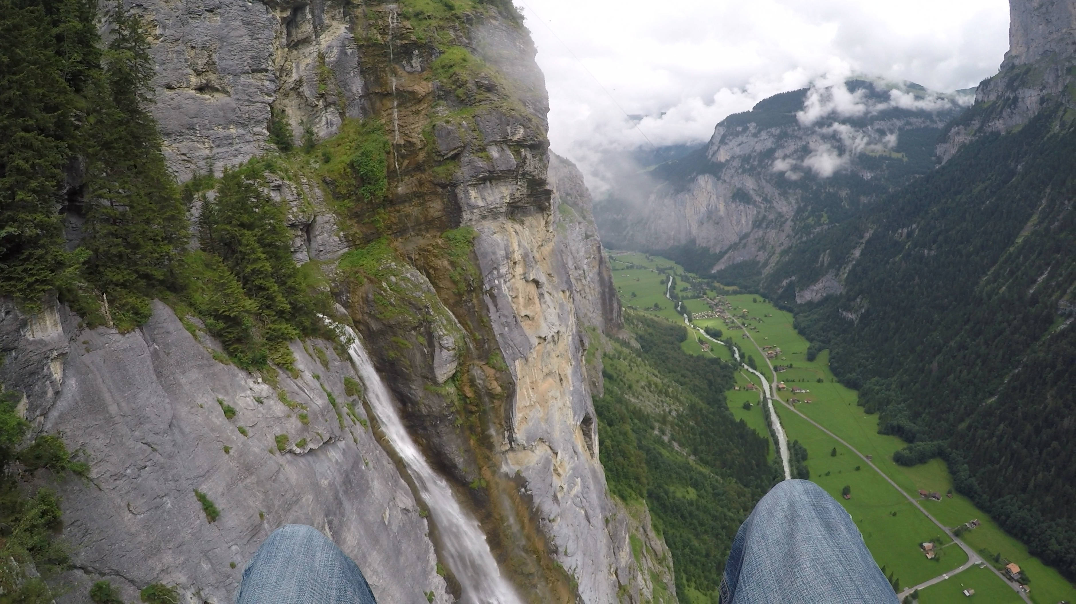 paragliding pilot POV, cliff edge, lush green valley, 2K Desktop Wallpaper