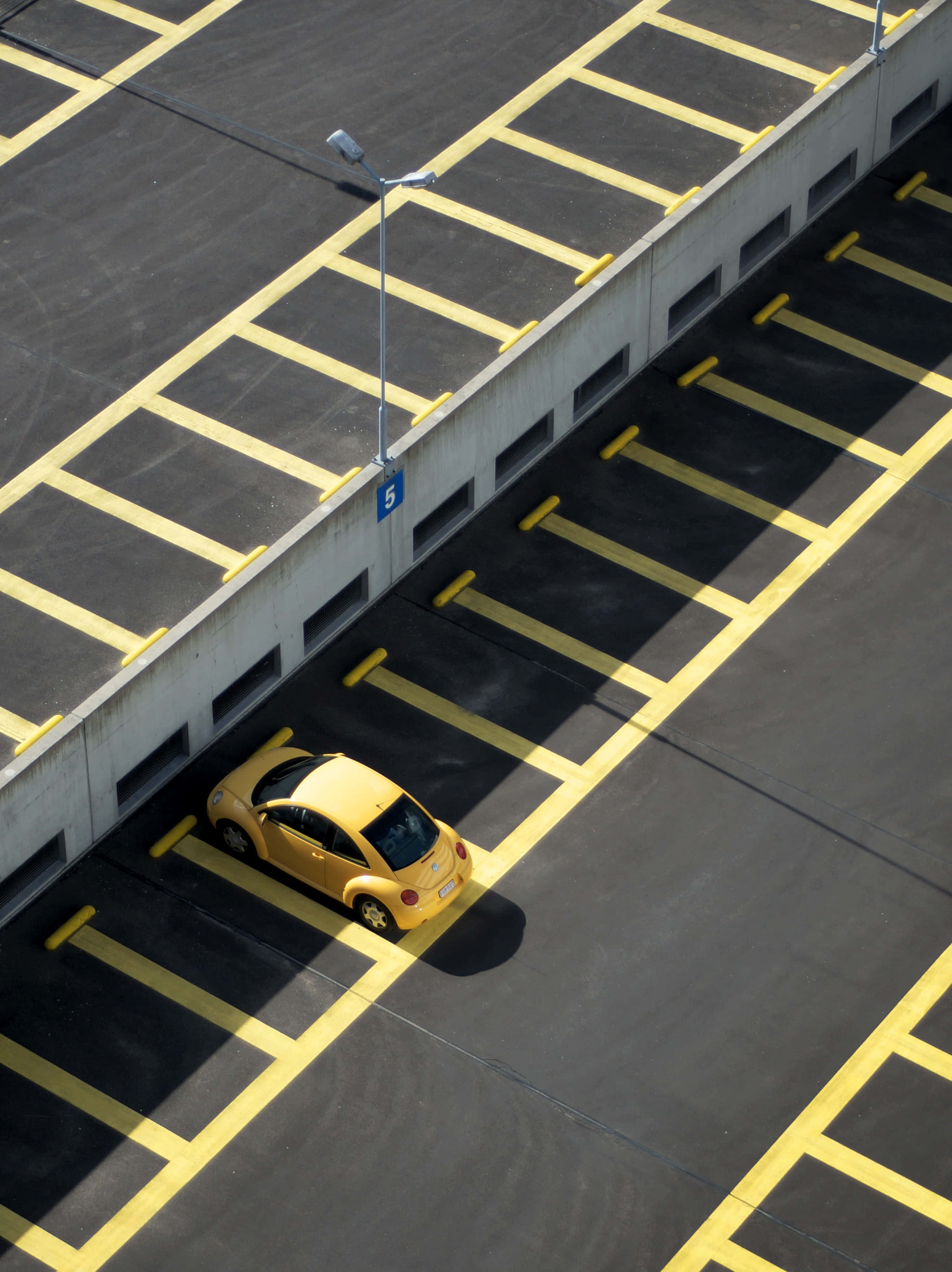 yellow car, vast empty parking garage, bold yellow lines, 2K Phone Wallpaper