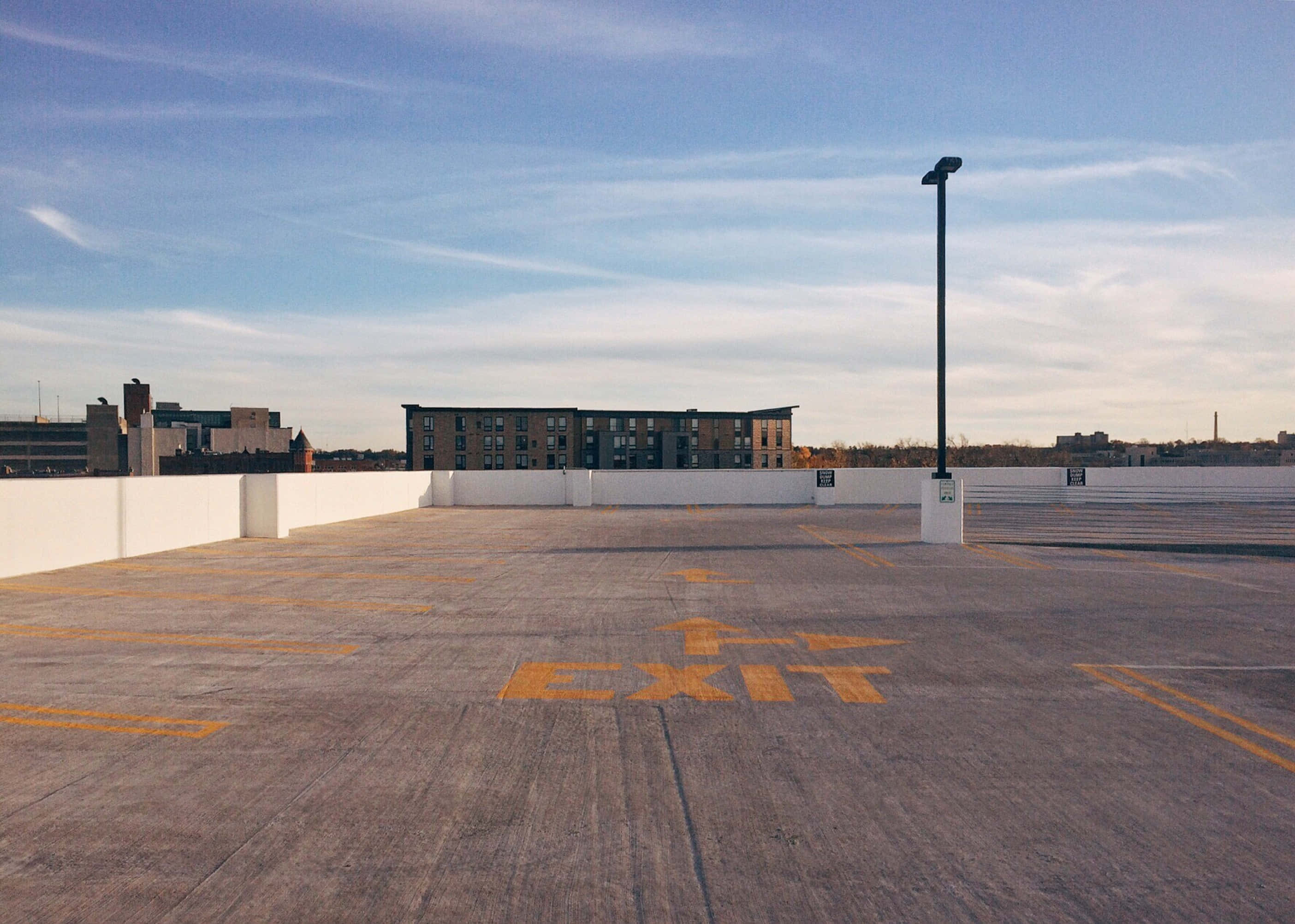 rooftop parking lot, faded yellow exit markings, clear blue sky, 2K Desktop Wallpaper