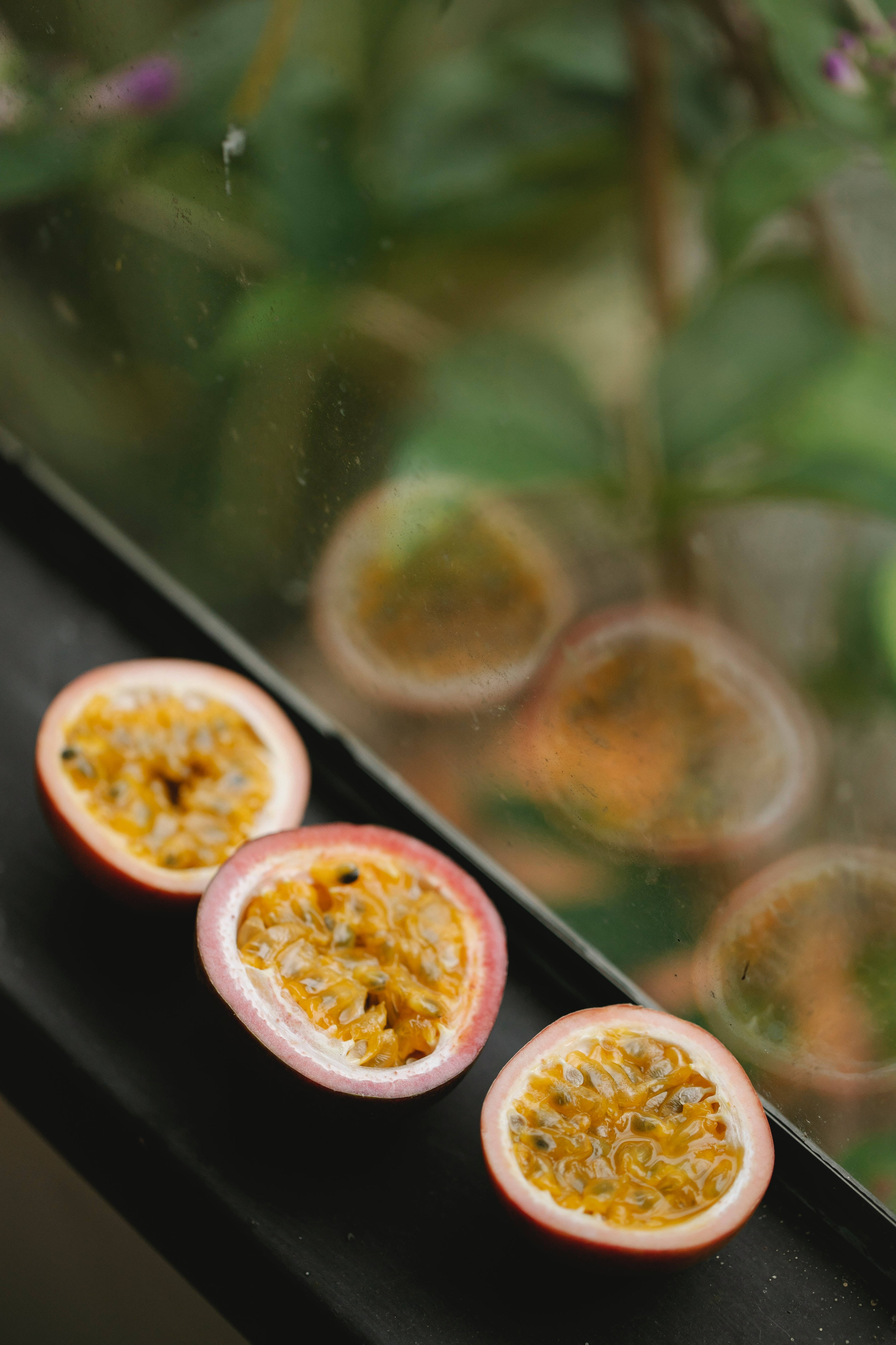 three sliced passion fruit, vibrant yellow pulp, black seeds, 4K Phone Wallpaper