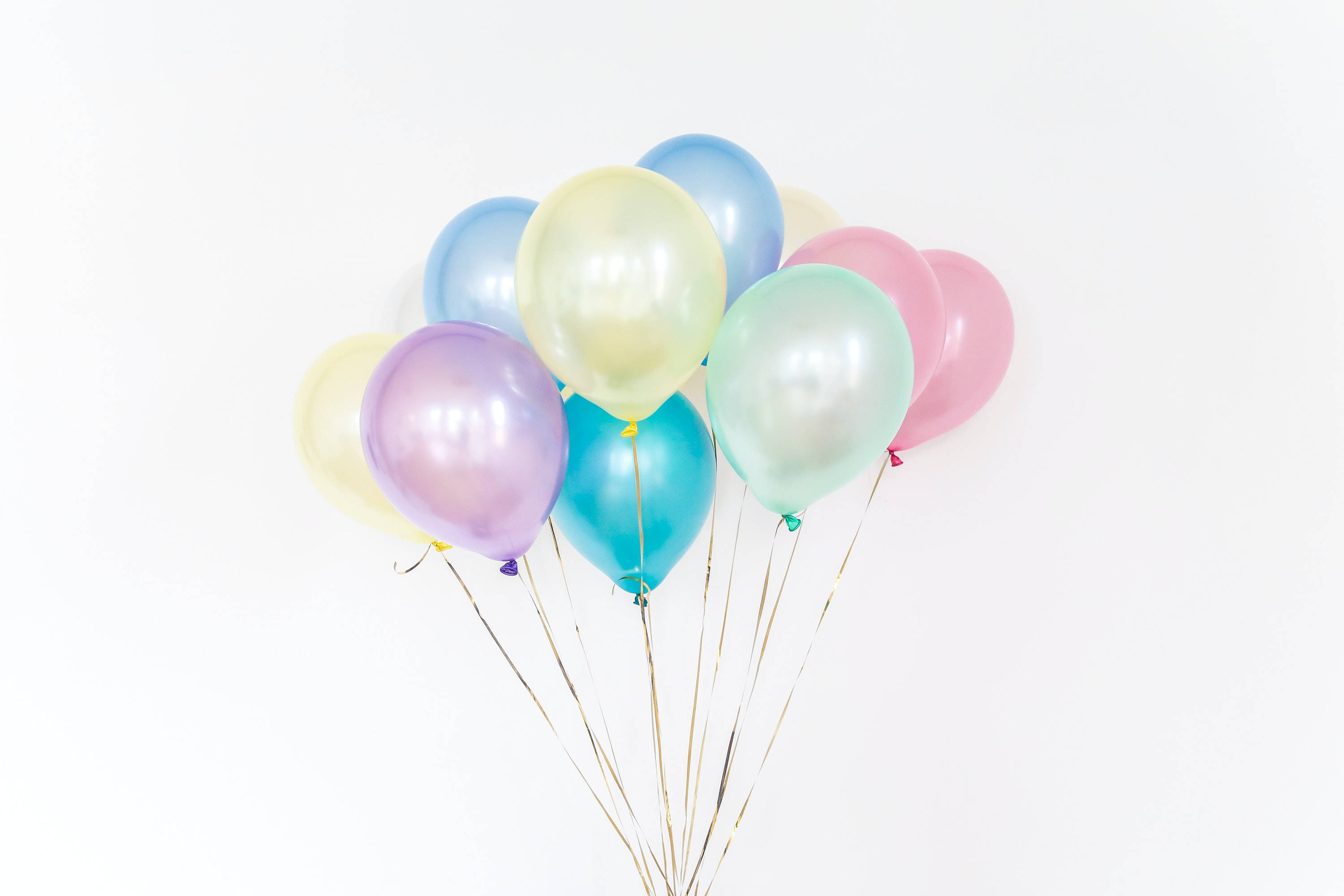 pastel-colored metallic balloons, gold strings, clean white background, 2K Desktop Wallpaper