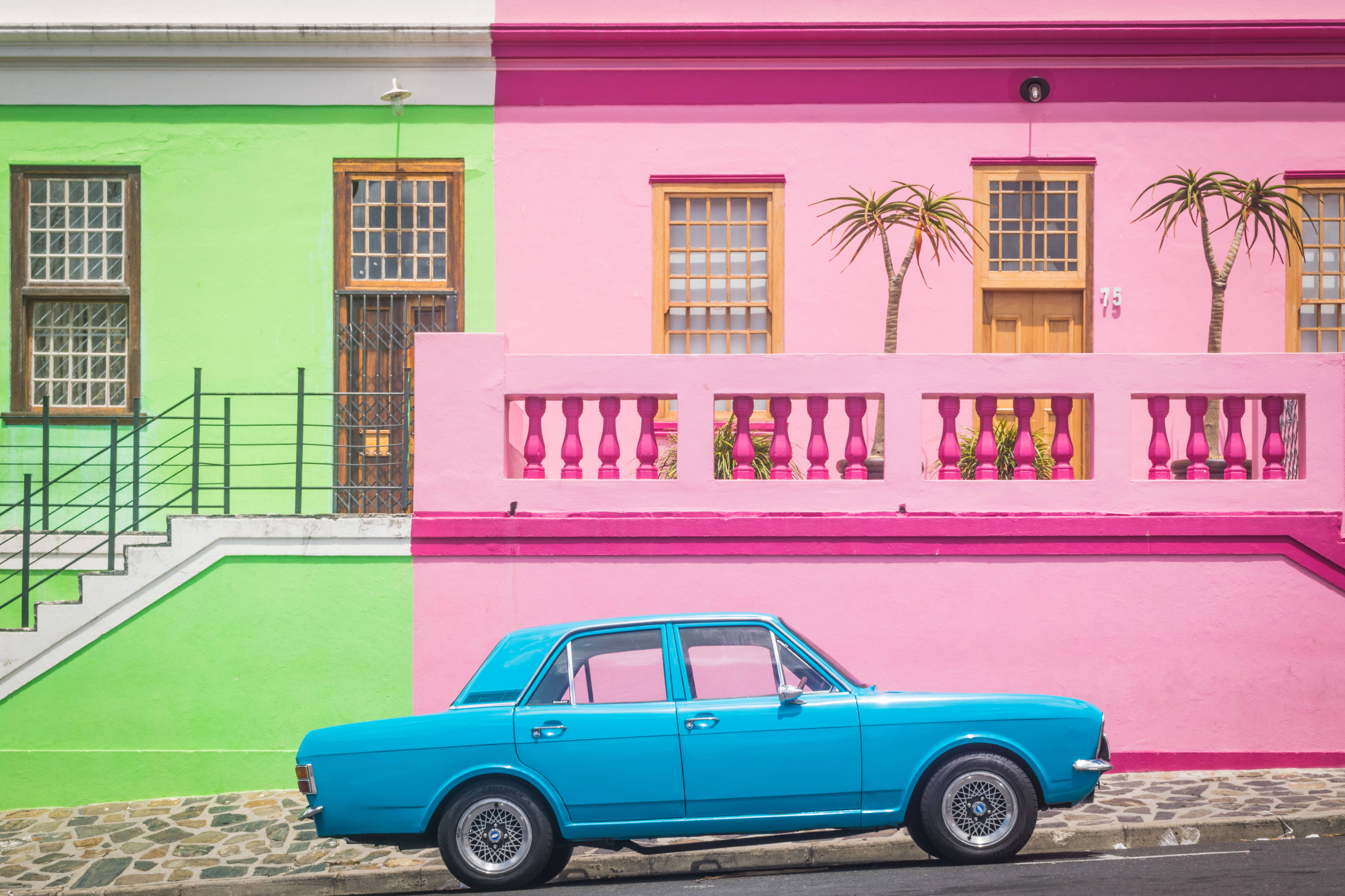 vintage blue car, vividly painted pink and green building, wooden windows, 5K Desktop Wallpaper