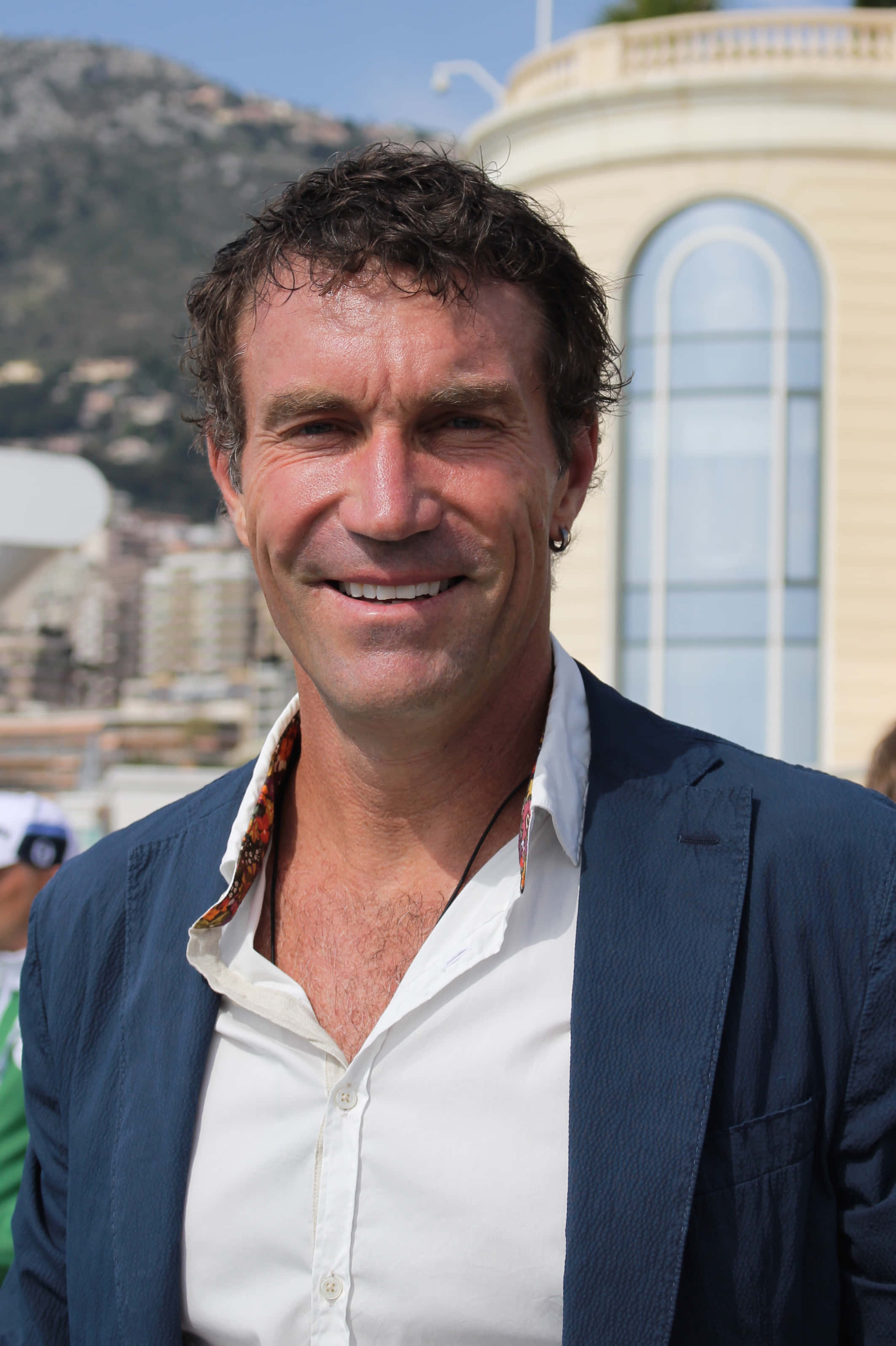 Pat Cash, blue blazer, sunlit coastal cityscape, 2K Phone Wallpaper