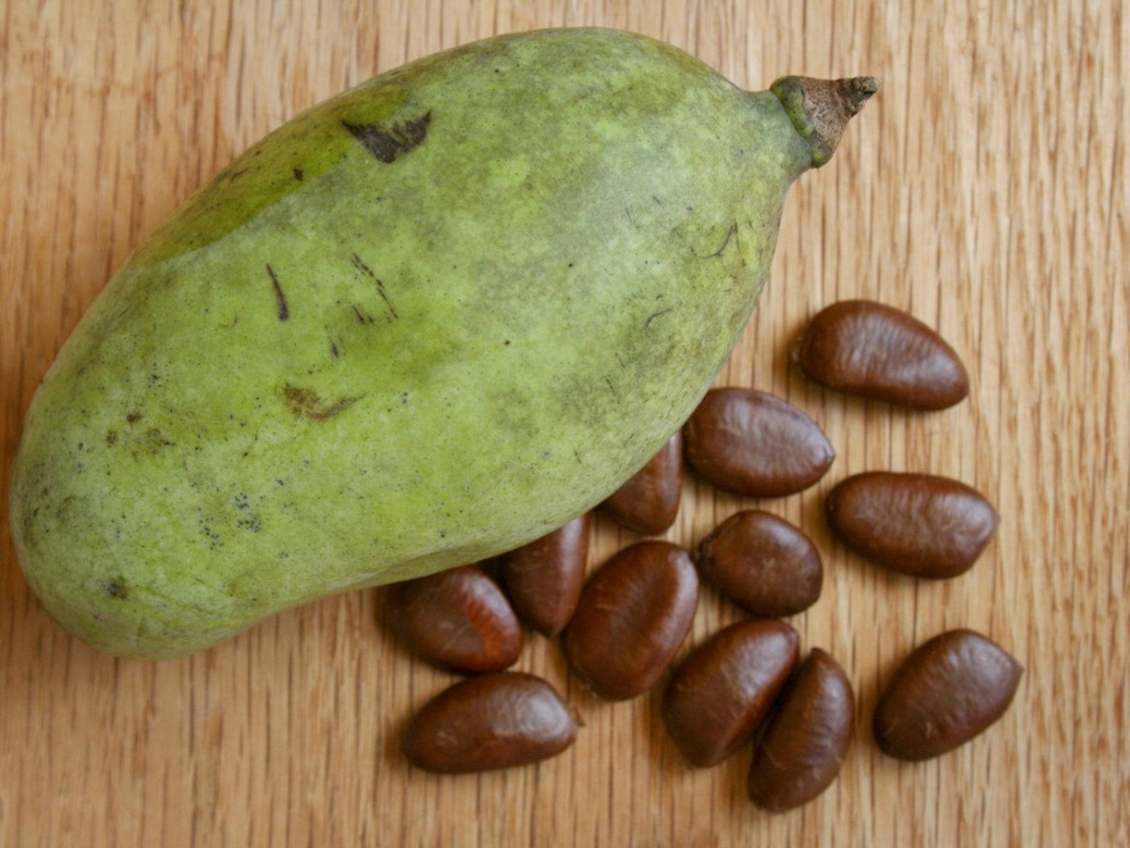 pawpaw fruit, brown seeds, light wooden surface, HD Desktop Wallpaper