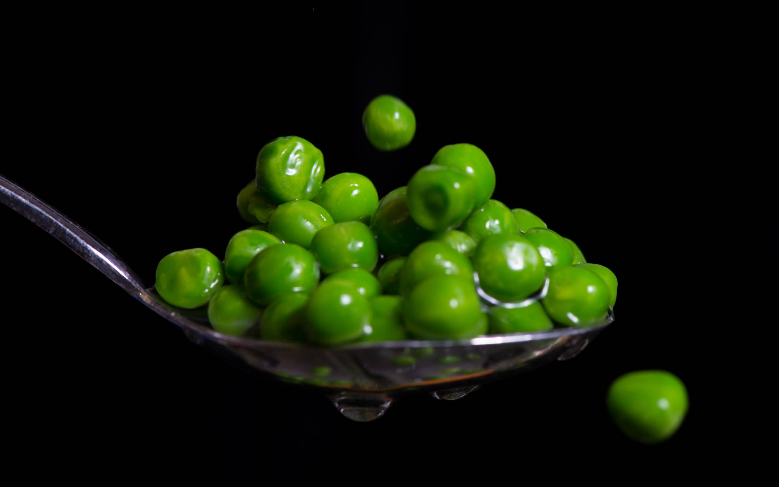 metallic spoon, fresh green peas, stark black background, 2K Desktop Wallpaper
