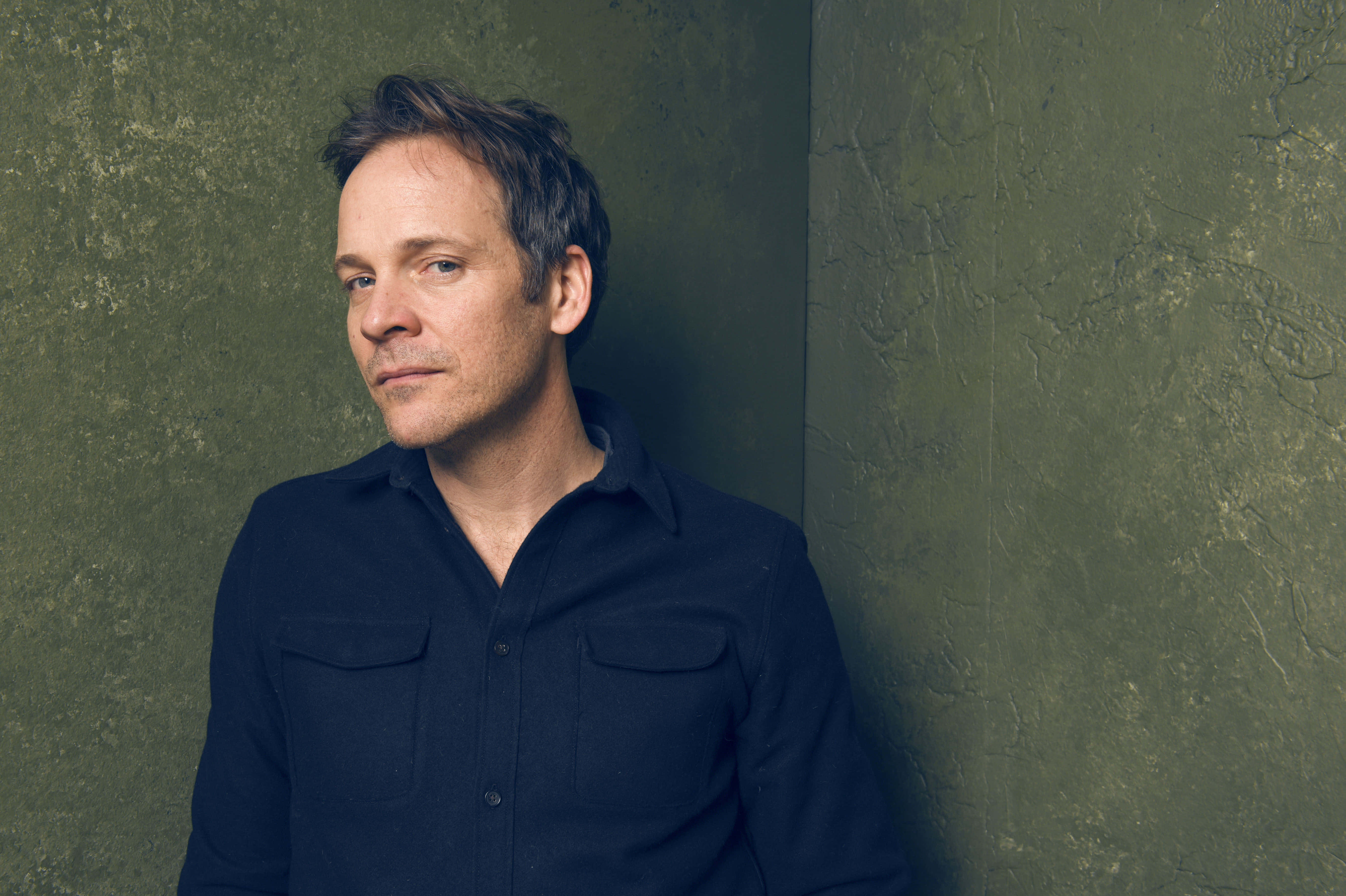 Peter Sarsgaard, black suit, textured olive green wall, 5K Desktop Wallpaper
