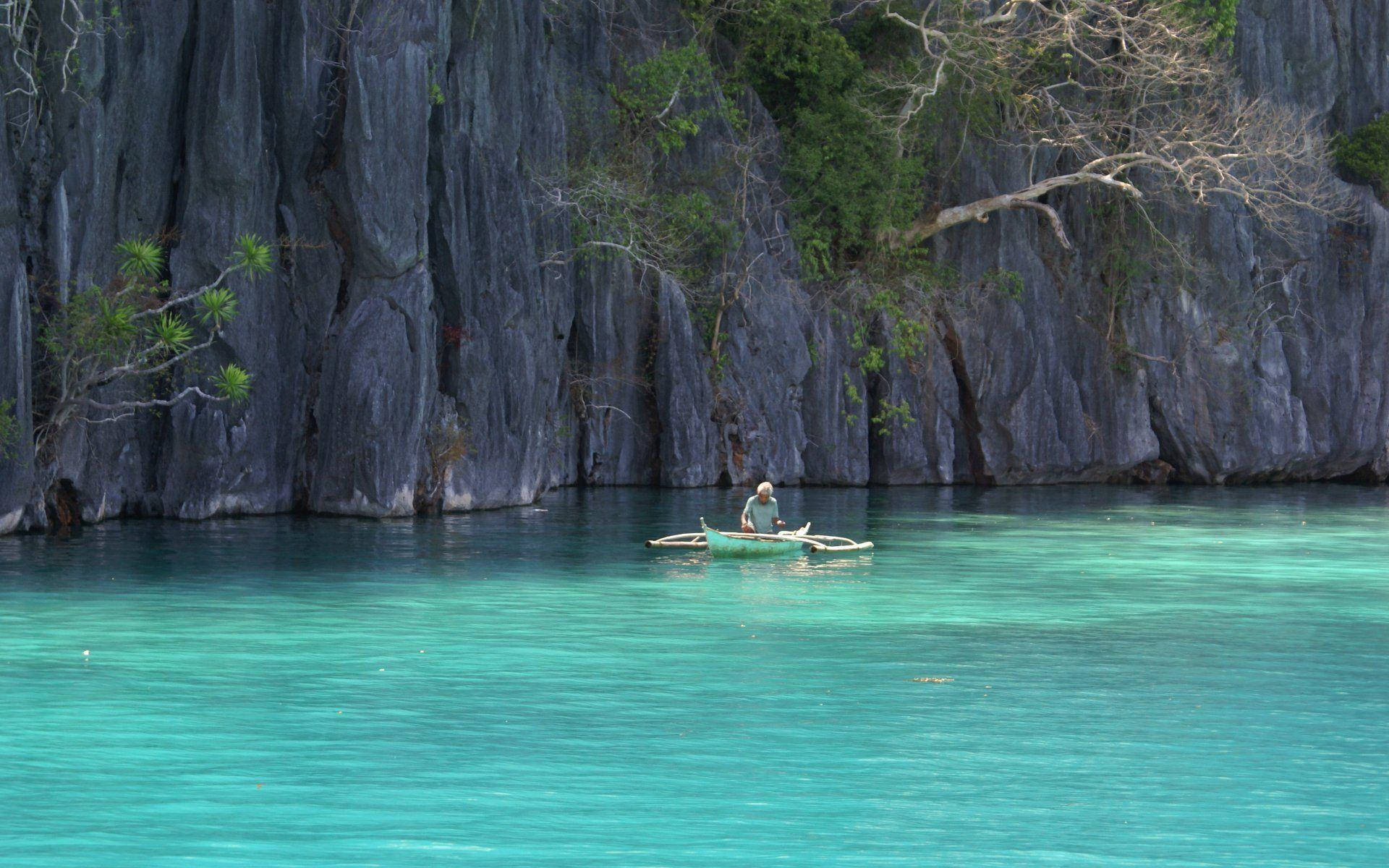 crystal clear turquoise waters, towering dark limestone cliffs, lone fisherman, Full HD Desktop Wallpaper