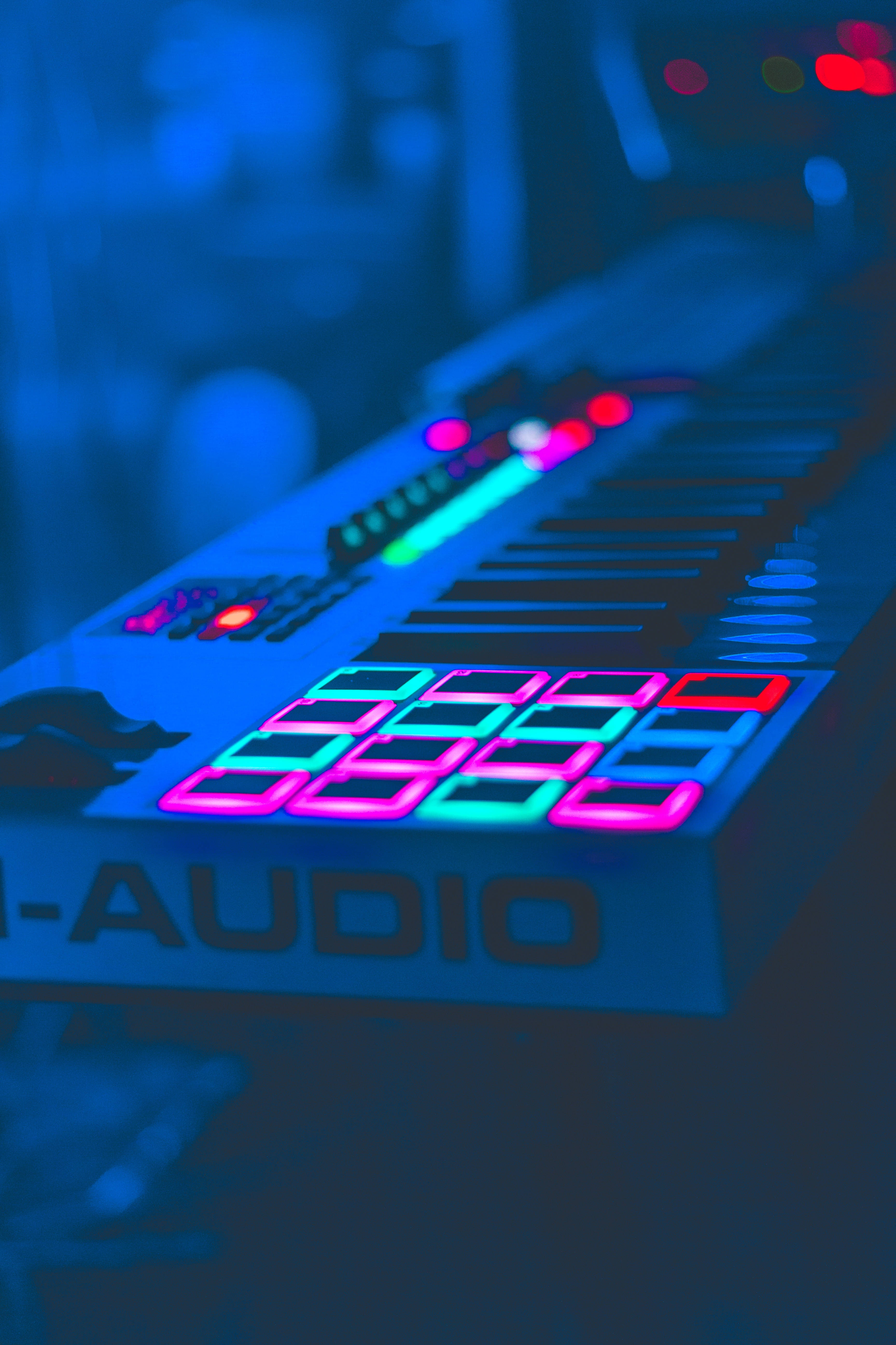 glowing blue and pink MIDI keyboard, illuminated pads and knobs, dimly lit studio, 5K Phone Wallpaper