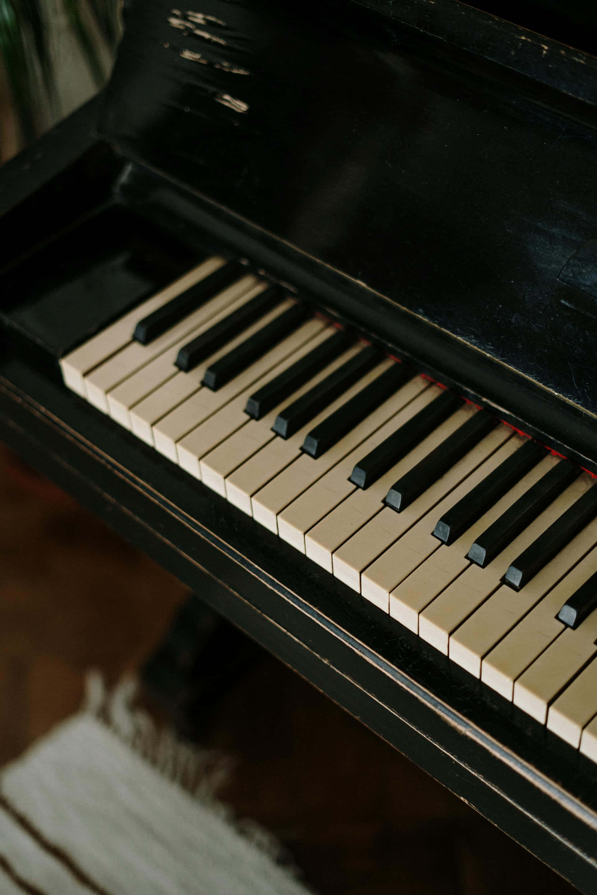 vintage black upright piano, worn keys, fringed rug, 2K Phone Wallpaper